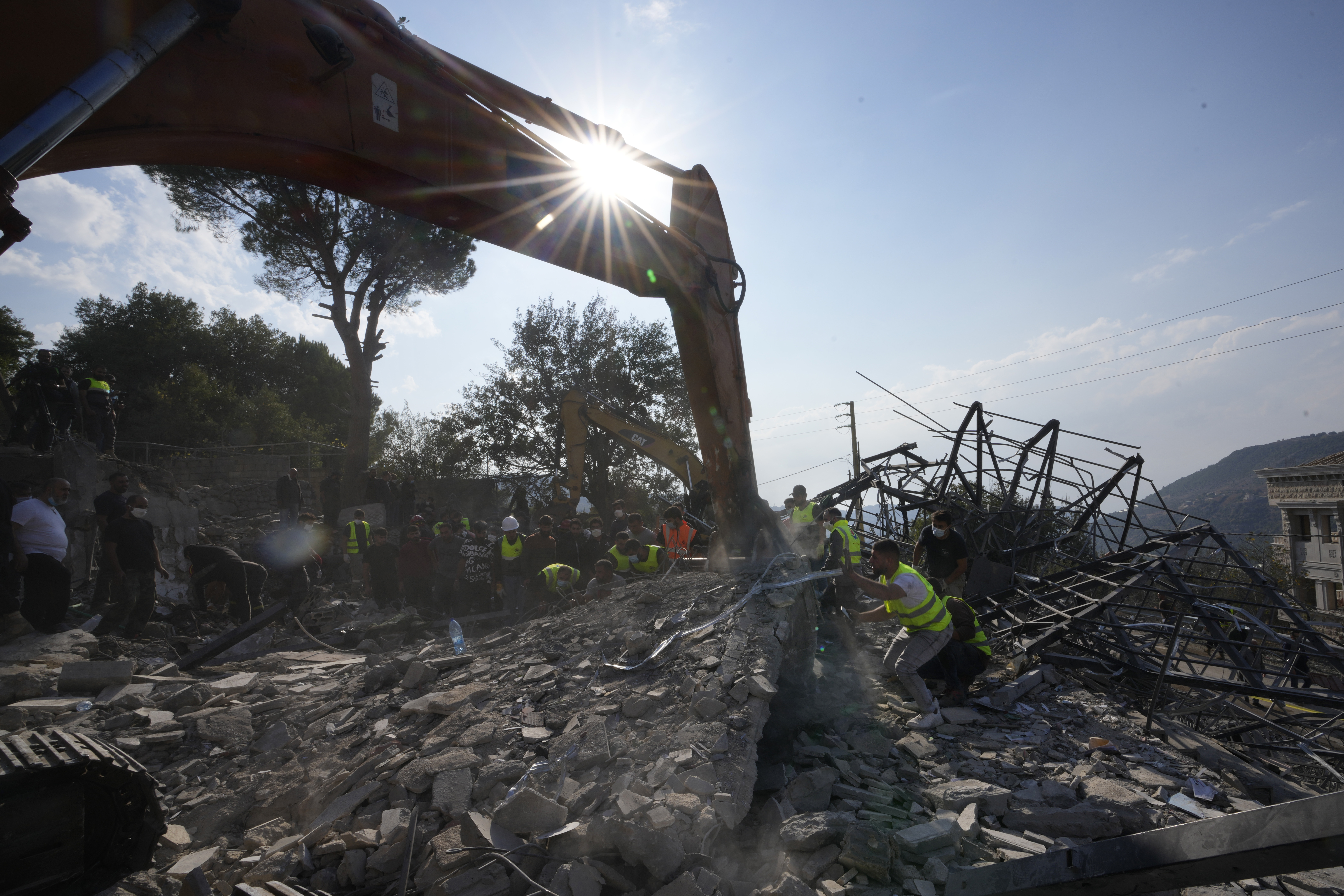 Rescue workers use an excavator to remove the rubble of a destroyed house hit in an Israeli airstrike, as they search for victims in Aalmat village, northern Lebanon, Sunday, Nov. 10, 2024. (AP Photo/Hassan Ammar)