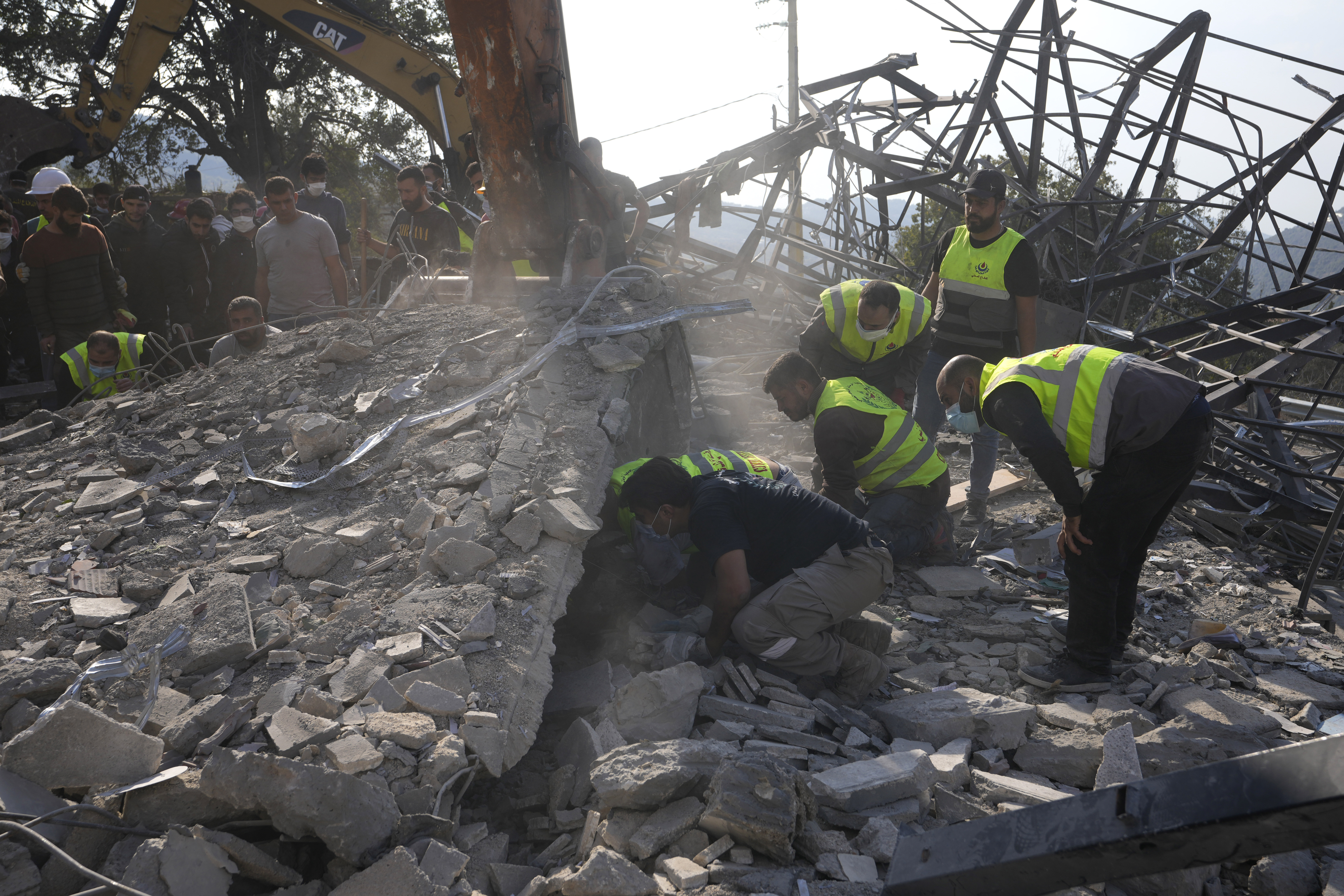 Rescue workers search for victims under the rubble of a destroyed house hit in an Israeli airstrike, in Aalmat village, northern Lebanon, Sunday, Nov. 10, 2024. (AP Photo/Hassan Ammar)