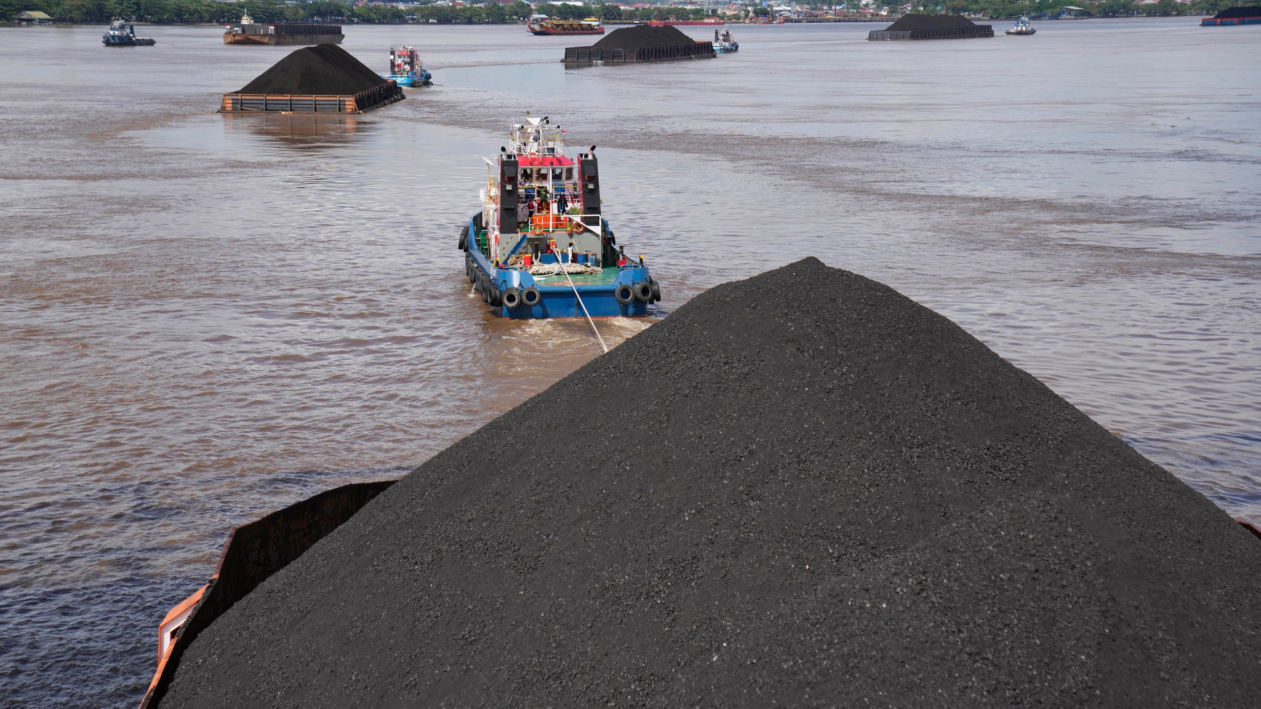 FILE - Tug boats pull barges fully loaded with coal on the Mahakam River in Samarinda, East Kalimantan, Indonesia, on Dec. 19, 2022. (AP Photo/Dita Alangkara, File)