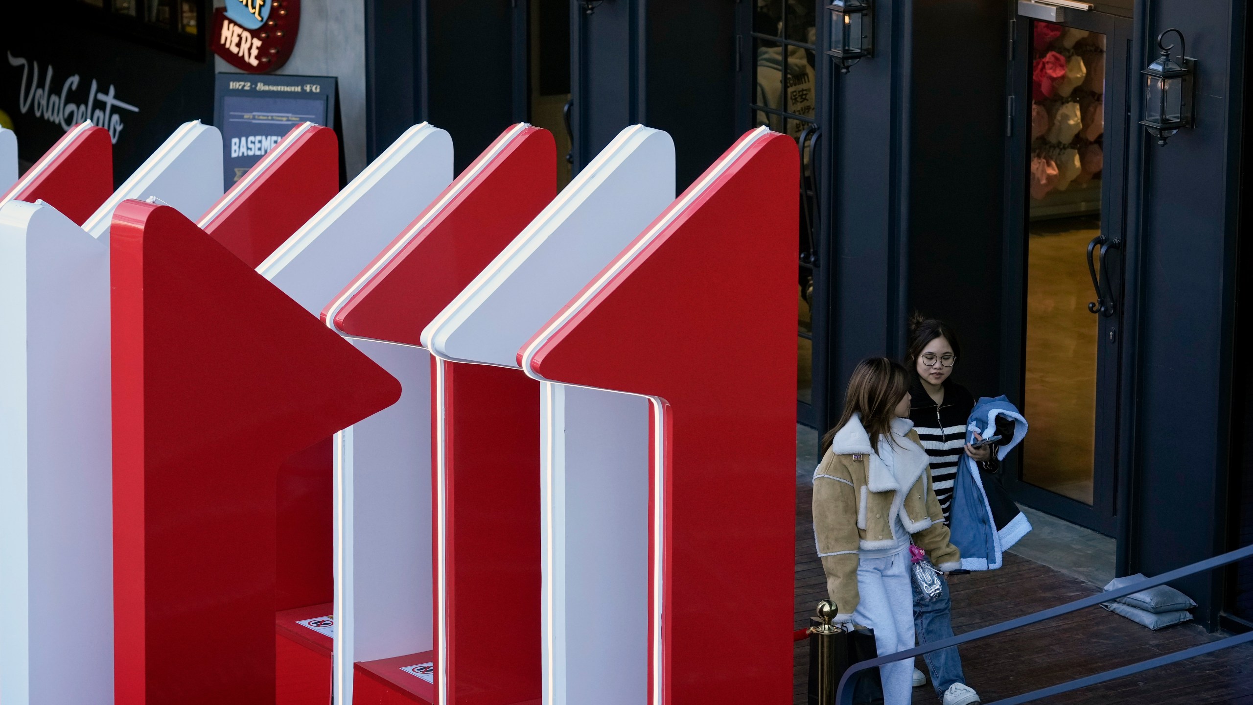 Women walk out from a fashion boutique near a display promoting the China popular e-commerce sales, the "Singles' Day" global online shopping festival, at a shopping mall in Beijing, on Nov. 4, 2024. (AP Photo/Andy Wong)