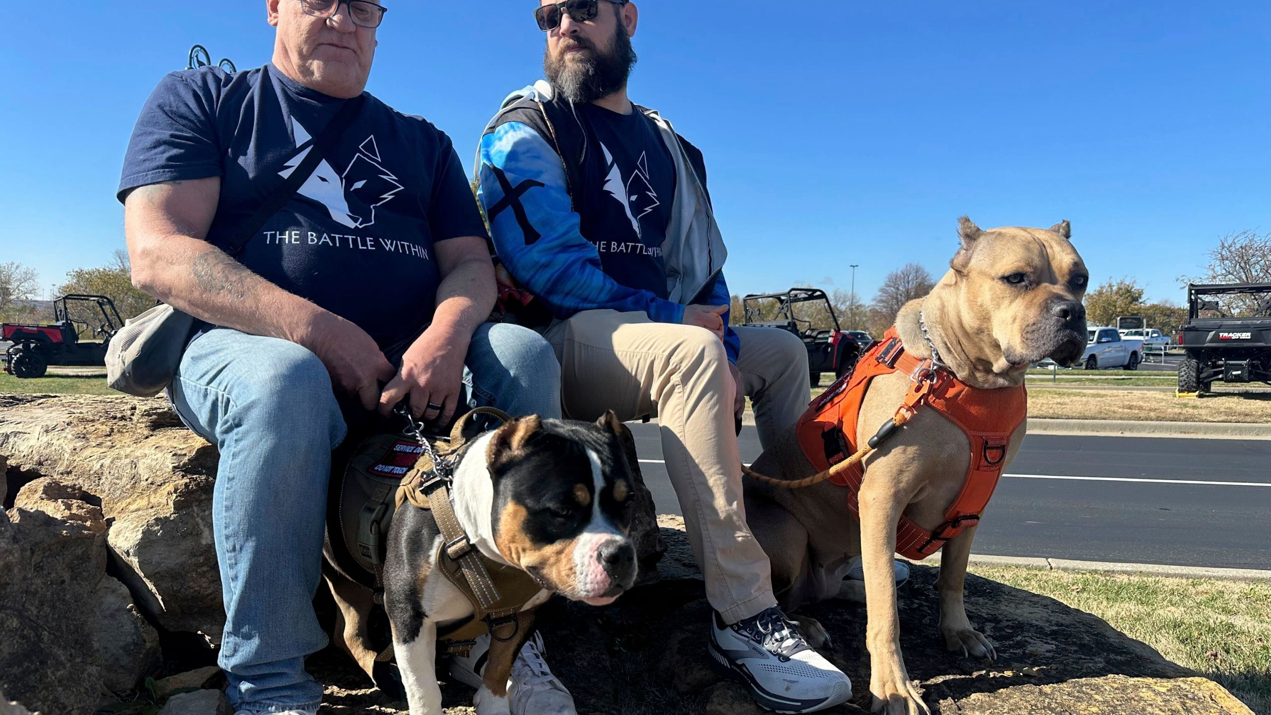 Retired Army First Sgt. Timothy Siebenmorgen, left, and retired Marine Corps Cpl. Mark Atkinson sit with their service dogs, Rosie and Lexi on Thursday, Nov. 7, 2024, in Kansas City, Kan., during a group training session. Both veterans are part of Dogs 4 Valor that helps retired veterans and first responders in the Kansas City area work with their service dogs to help manage depression, anxiety and other challenges. (AP Photo/Nick Ingram)