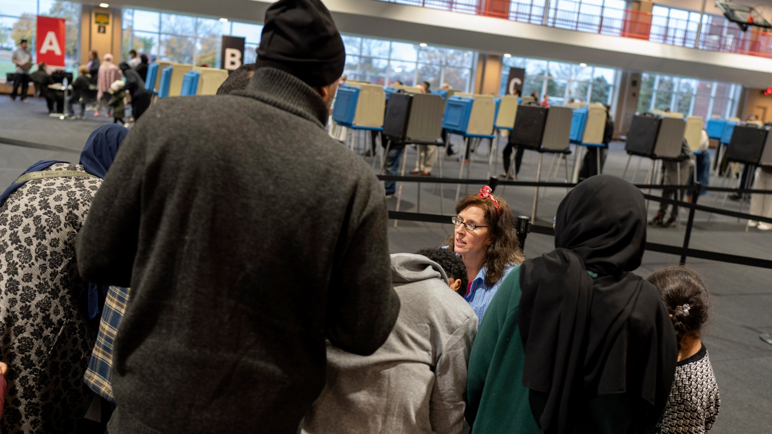 An election official helps check in voters at Ford Community and Performing Arts Center on the last day of early in-person voting, Sunday, Nov. 3, 2024, in Dearborn, Mich., the nation's largest Arab-majority city. (AP Photo/David Goldman)