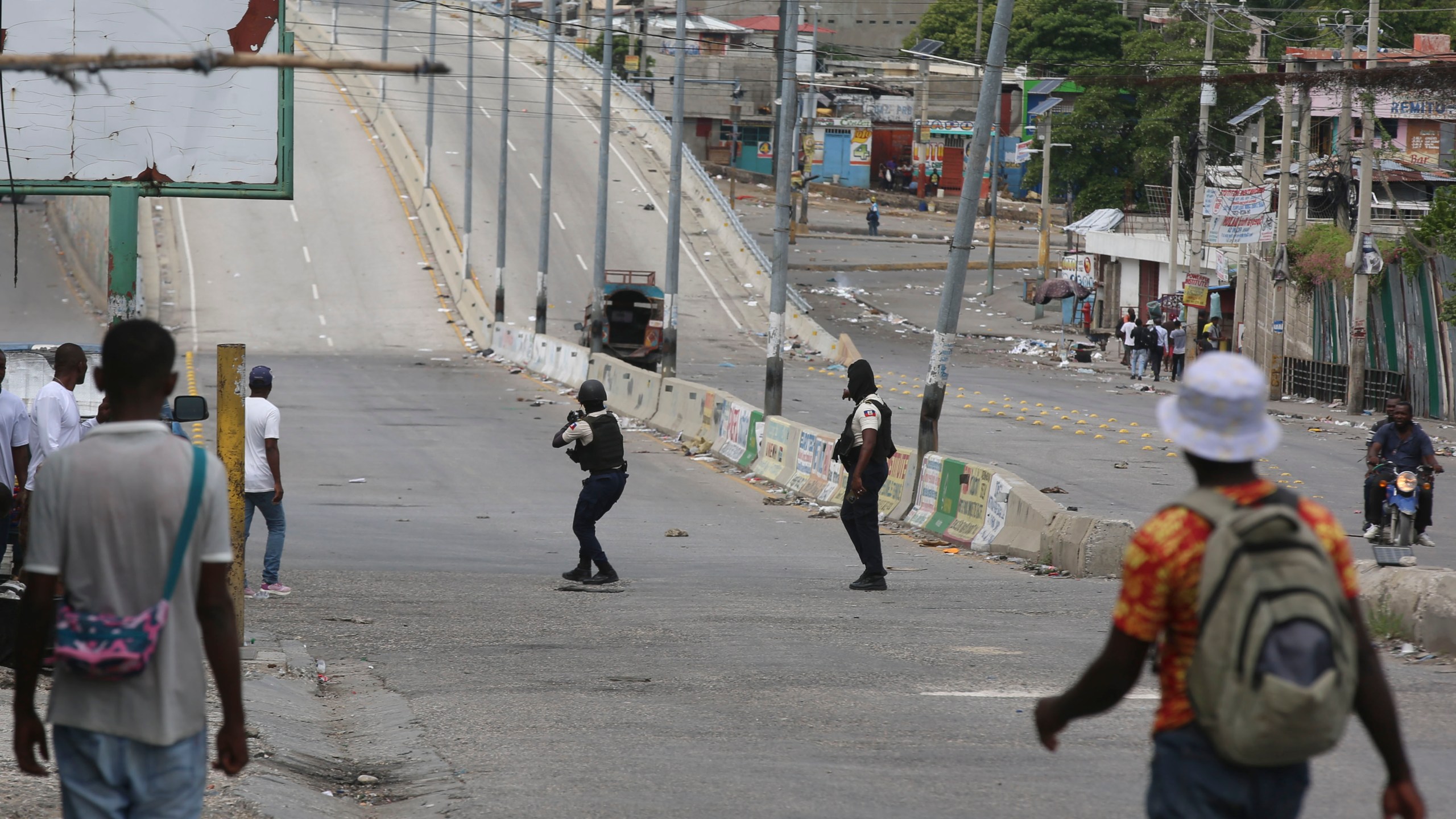 People watch as police officers exchange gunfire with gangs in Port-au-Prince, Haiti, Monday, Nov. 11, 2024. (AP Photo/Odelyn Joseph)