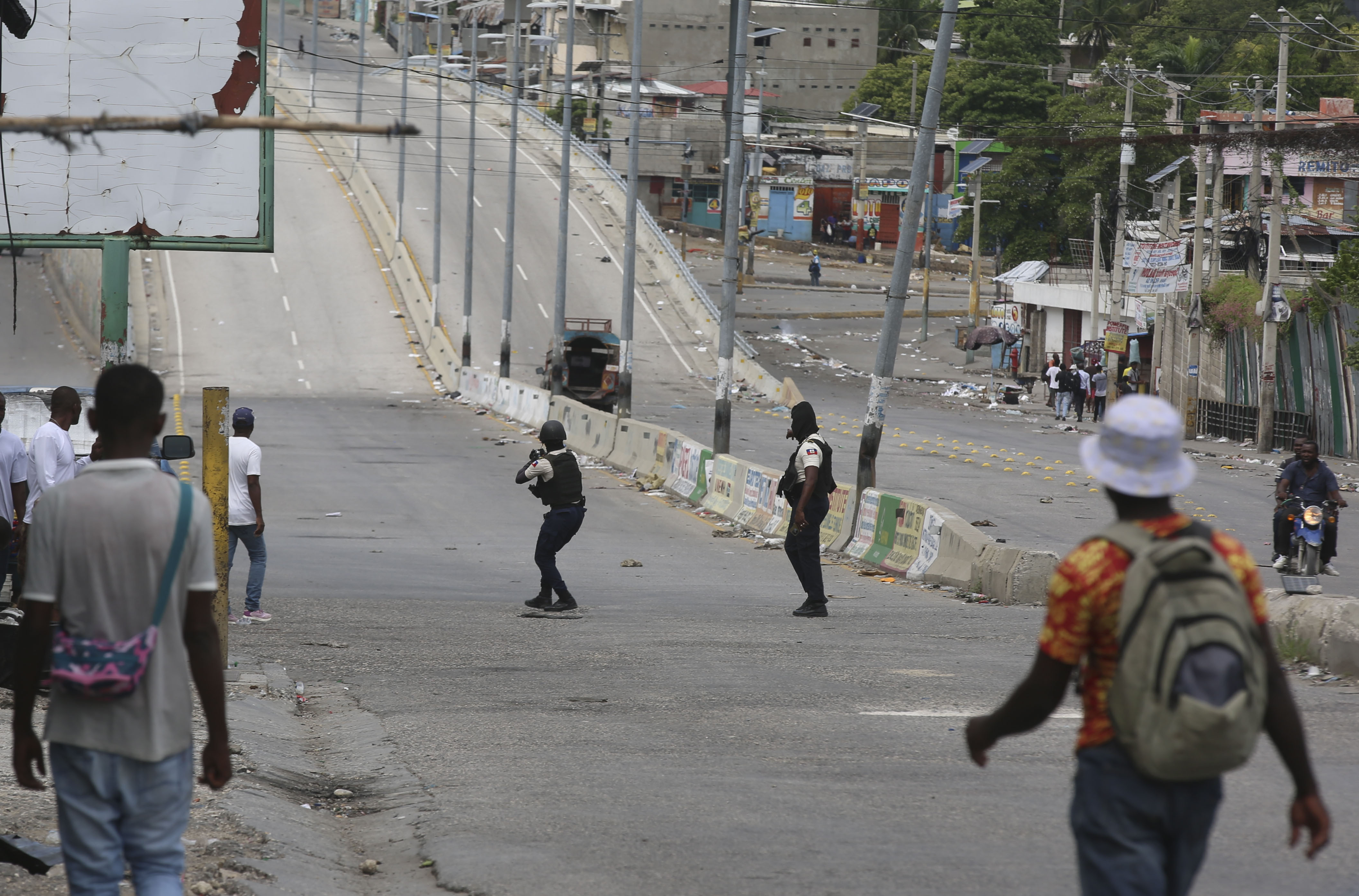 People watch as police officers exchange gunfire with gangs in Port-au-Prince, Haiti, Monday, Nov. 11, 2024. (AP Photo/Odelyn Joseph)