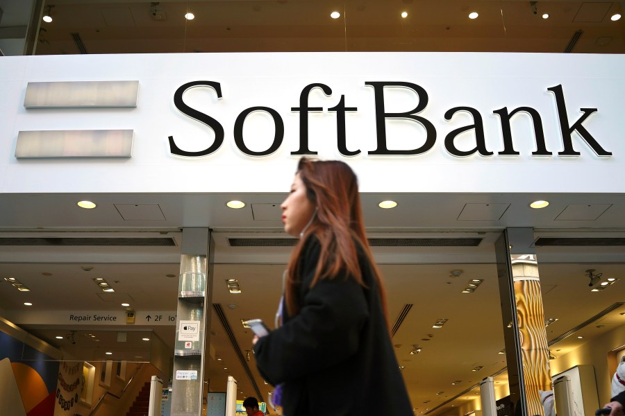 FILE - A woman walks in front of SoftBank store in Ginza shopping district in Tokyo, Jan. 20, 2020. (AP Photo/Eugene Hoshiko, File)