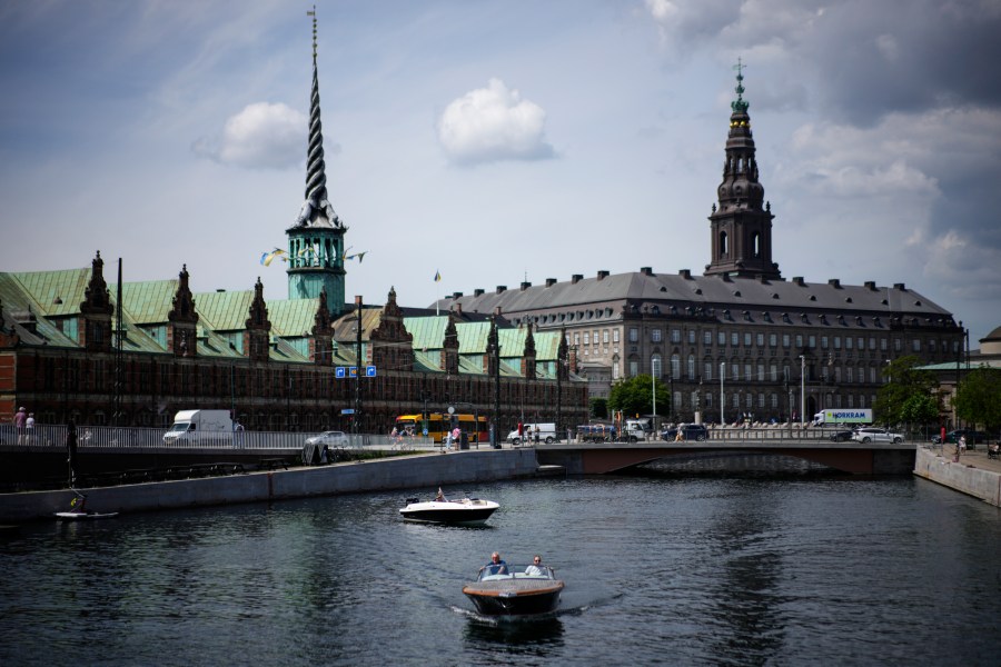 FILE - A boat wades through the Nyhavn river, with the Old Stock Exchange building left in the background, in Copenhagen, Denmark, on June 29, 2022. (AP Photo/Daniel Cole, File)