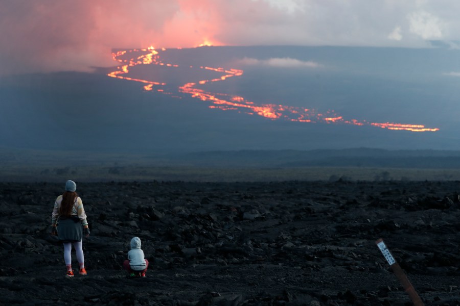 FILE - Spectators watch the lava flow down the mountain from the Mauna Loa eruption, Tuesday, Nov. 29, 2022, near Hilo, Hawaii. (AP Photo/Marco Garcia, File)