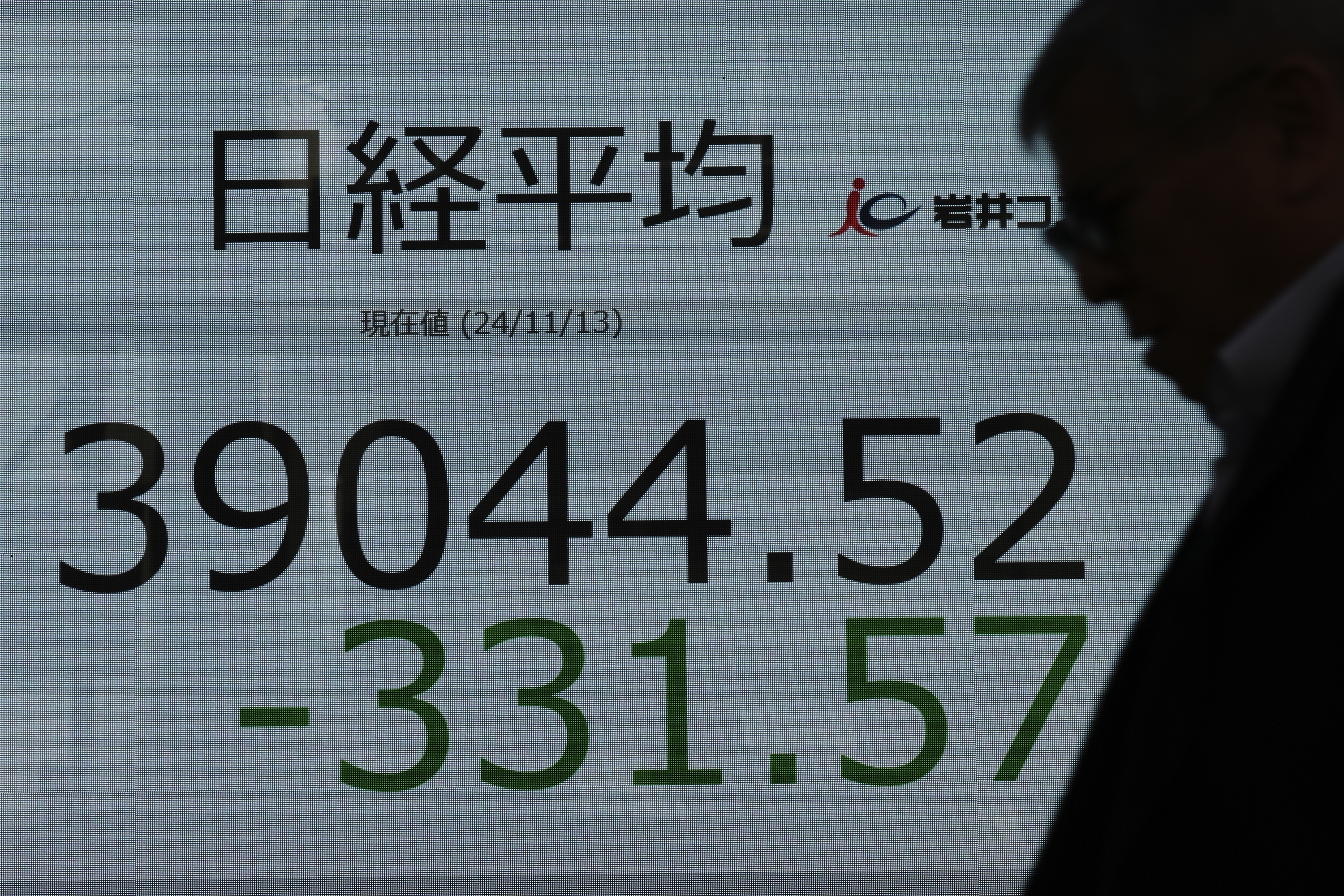 A person walks in front of an electronic stock board showing Japan's Nikkei index at a securities firm Wednesday, Nov. 13, 2024, in Tokyo. (AP Photo/Eugene Hoshiko)