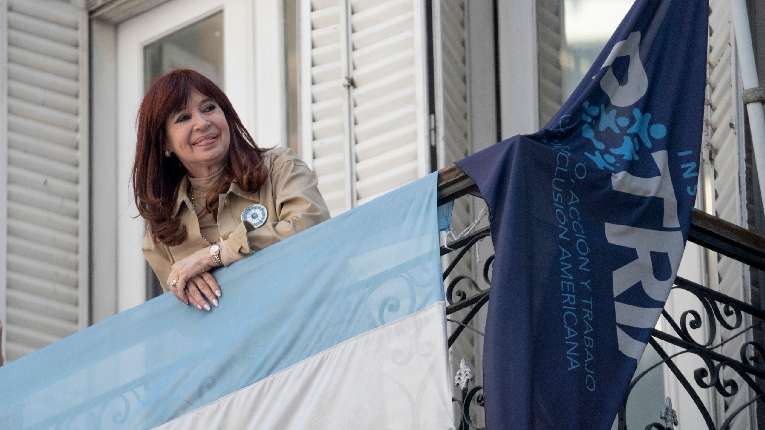 Former President Cristina Fernández smiles at supporters who have rallied outside her residence after a tribunal upheld a six-year sentence term and lifetime ban from holding public office sentence against Fernández, in Buenos Aires, Argentina, Wednesday, Nov. 13, 2024. (AP Photo/Victor R. Caivano)