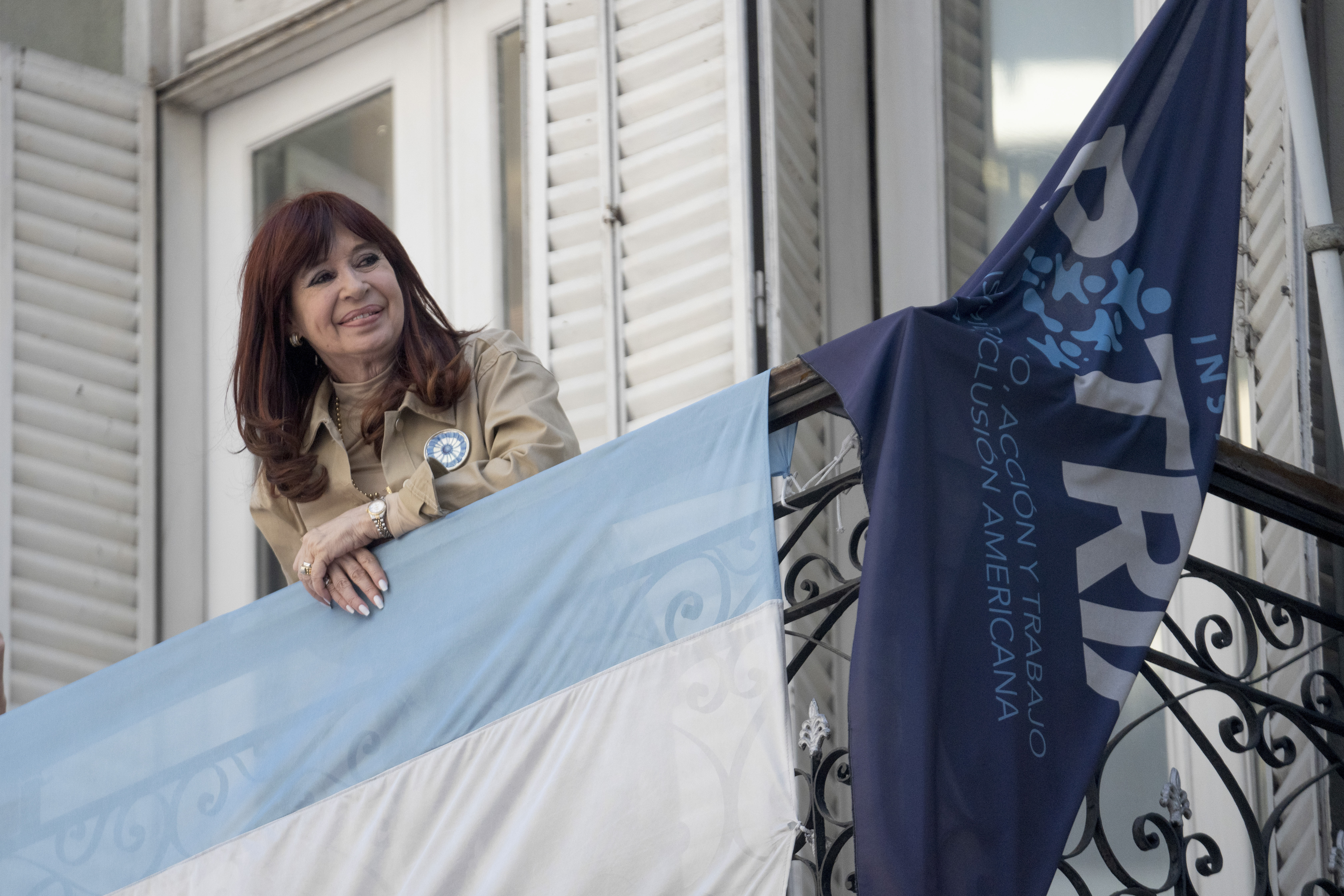 Former President Cristina Fernández smiles at supporters who have rallied outside her residence after a tribunal upheld a six-year sentence term and lifetime ban from holding public office sentence against Fernández, in Buenos Aires, Argentina, Wednesday, Nov. 13, 2024. (AP Photo/Victor R. Caivano)