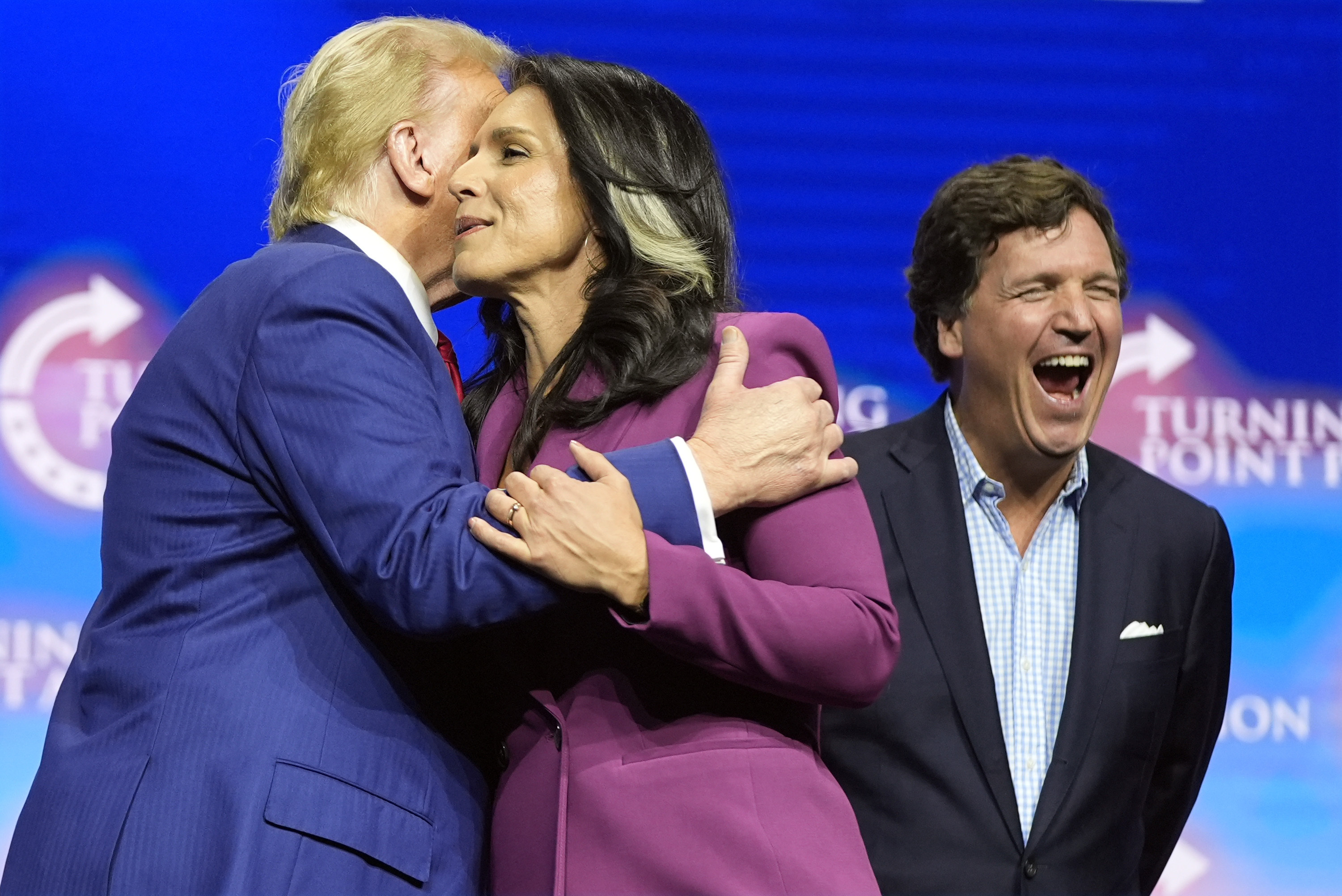 Former Democratic Rep. Tulsi Gabbard hugs Republican presidential nominee former President Donald Trump as Tucker Carlson yells during a campaign rally Wednesday, Oct. 23, 2024, in Duluth, Ga. (AP Photo/Alex Brandon)