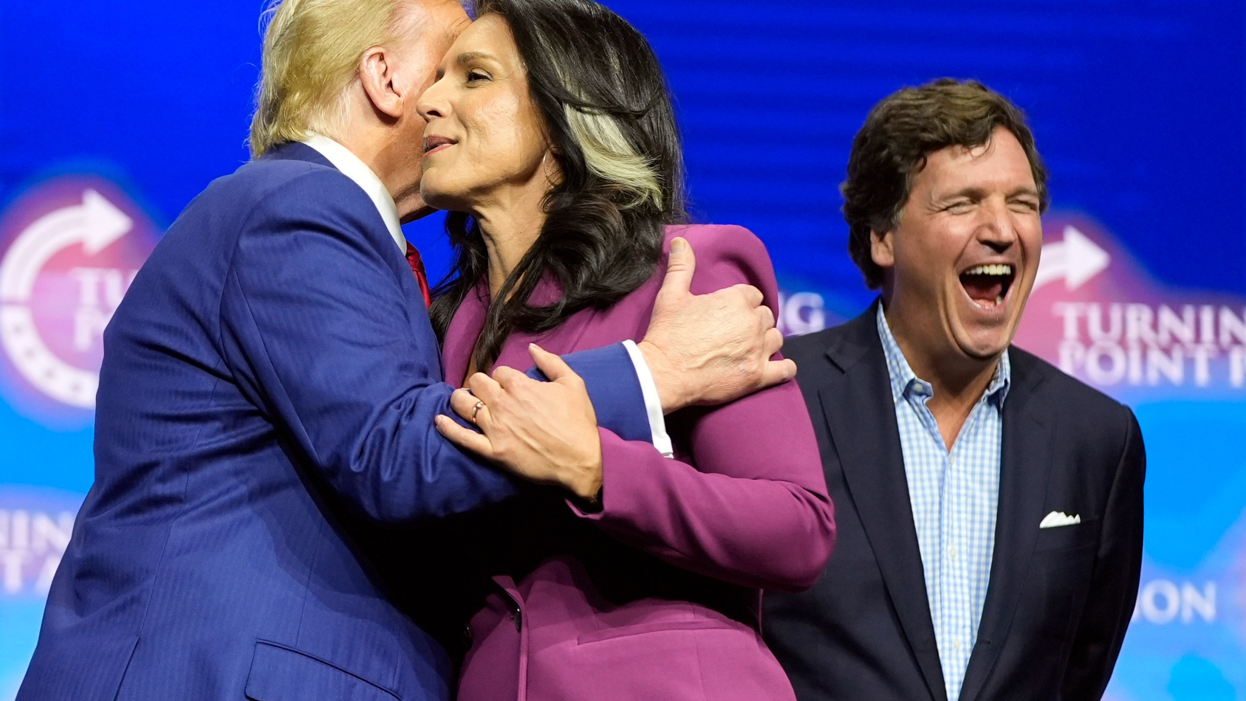 Former Democratic Rep. Tulsi Gabbard hugs Republican presidential nominee former President Donald Trump as Tucker Carlson yells during a campaign rally Wednesday, Oct. 23, 2024, in Duluth, Ga. (AP Photo/Alex Brandon)