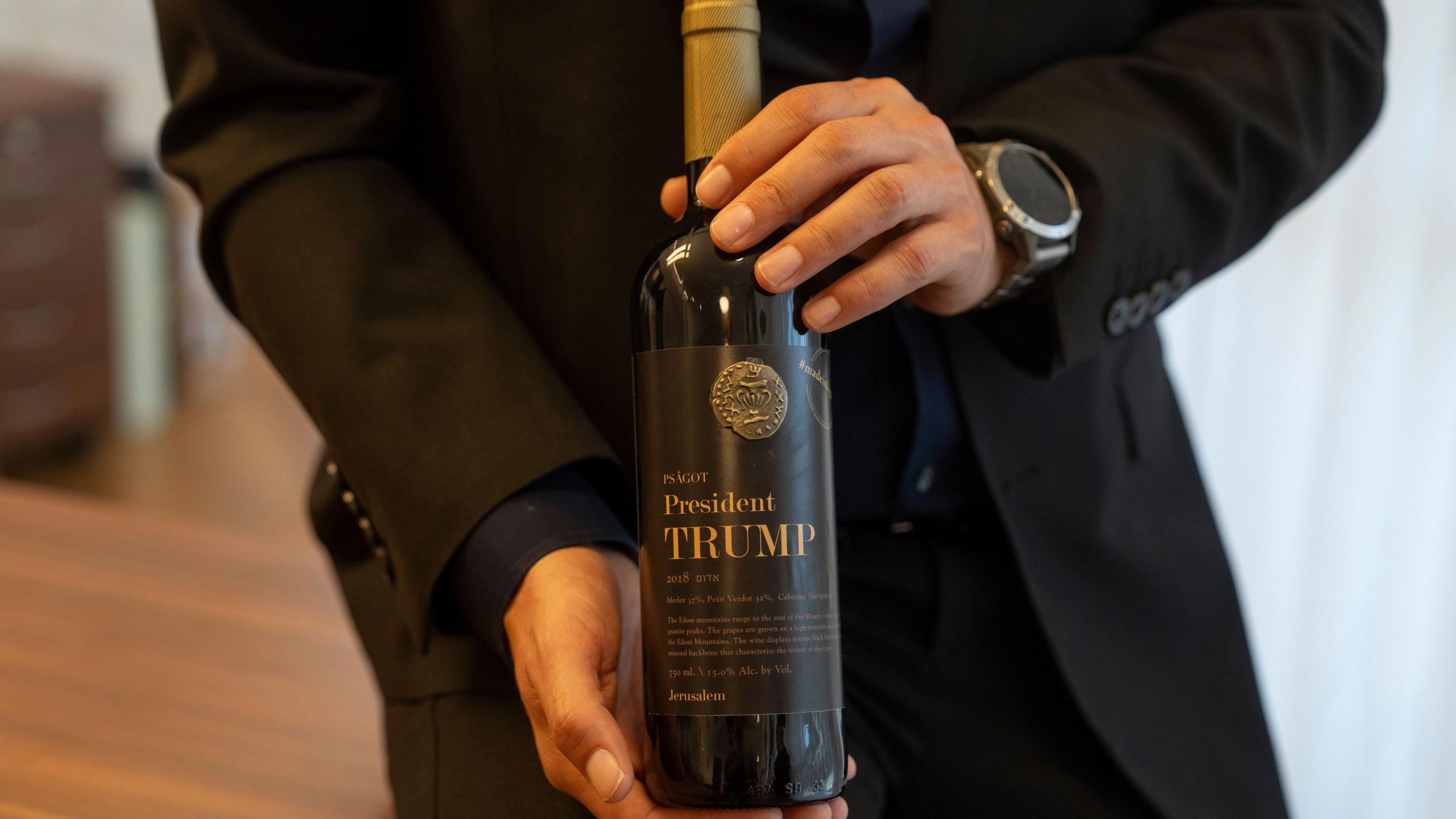 Israel Ganz, chairman of the Yesha settlers council and head of the Mateh Binyamin Regional Council, poses for a portrait holding a bottle of wine bearing the name of U.S. President-elect Donald Trump in the Shaar Binyamin Industrial Park in the West Bank, Monday, Nov. 11, 2024. (AP Photo/Ohad Zwigenberg)