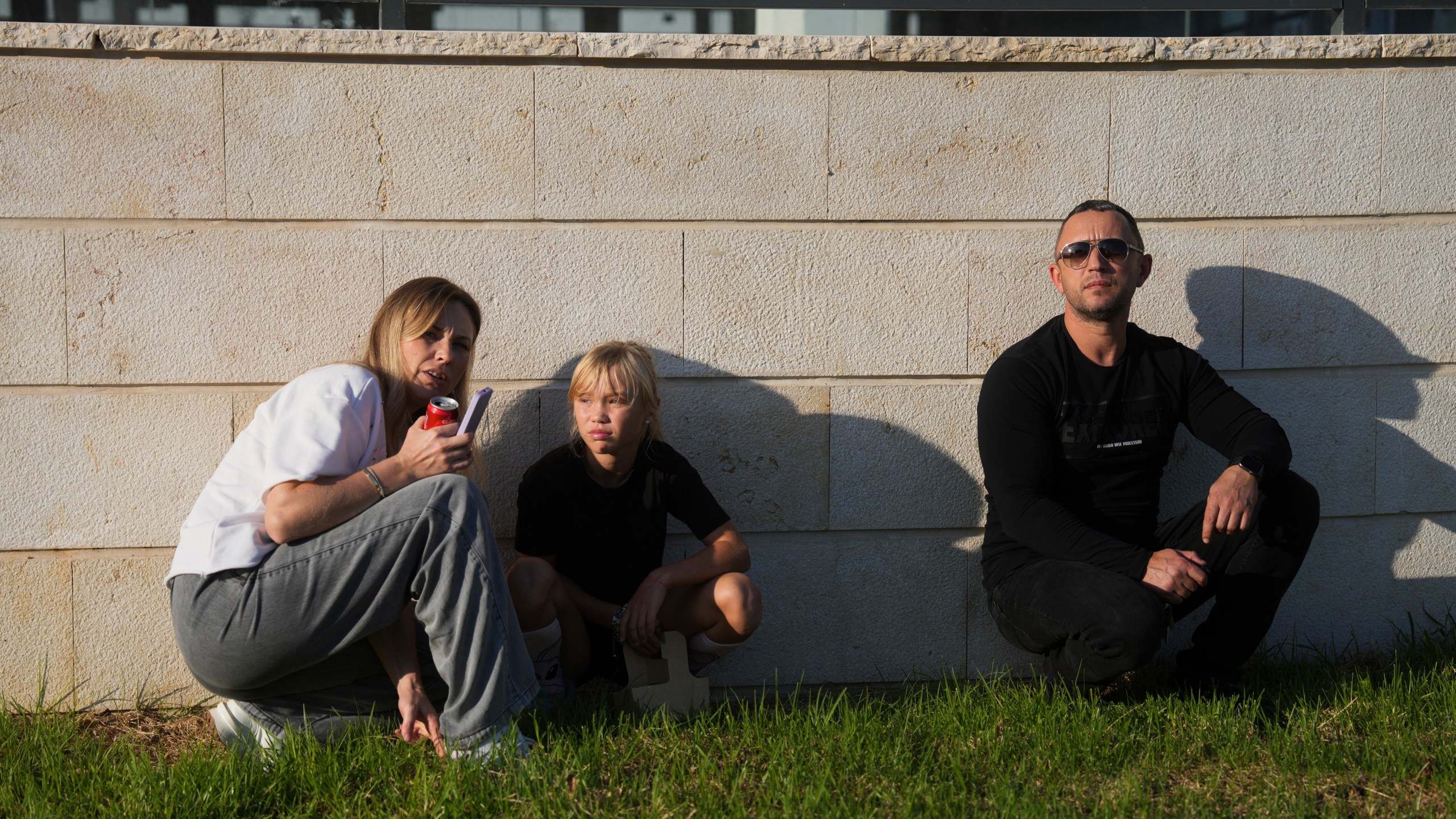 People take cover as a siren sounds a warning of incoming rockets fired from Lebanon, in Kiryat Yam, northern Israel, Wednesday, Nov. 13, 2024. (AP Photo/Ohad Zwigenberg)