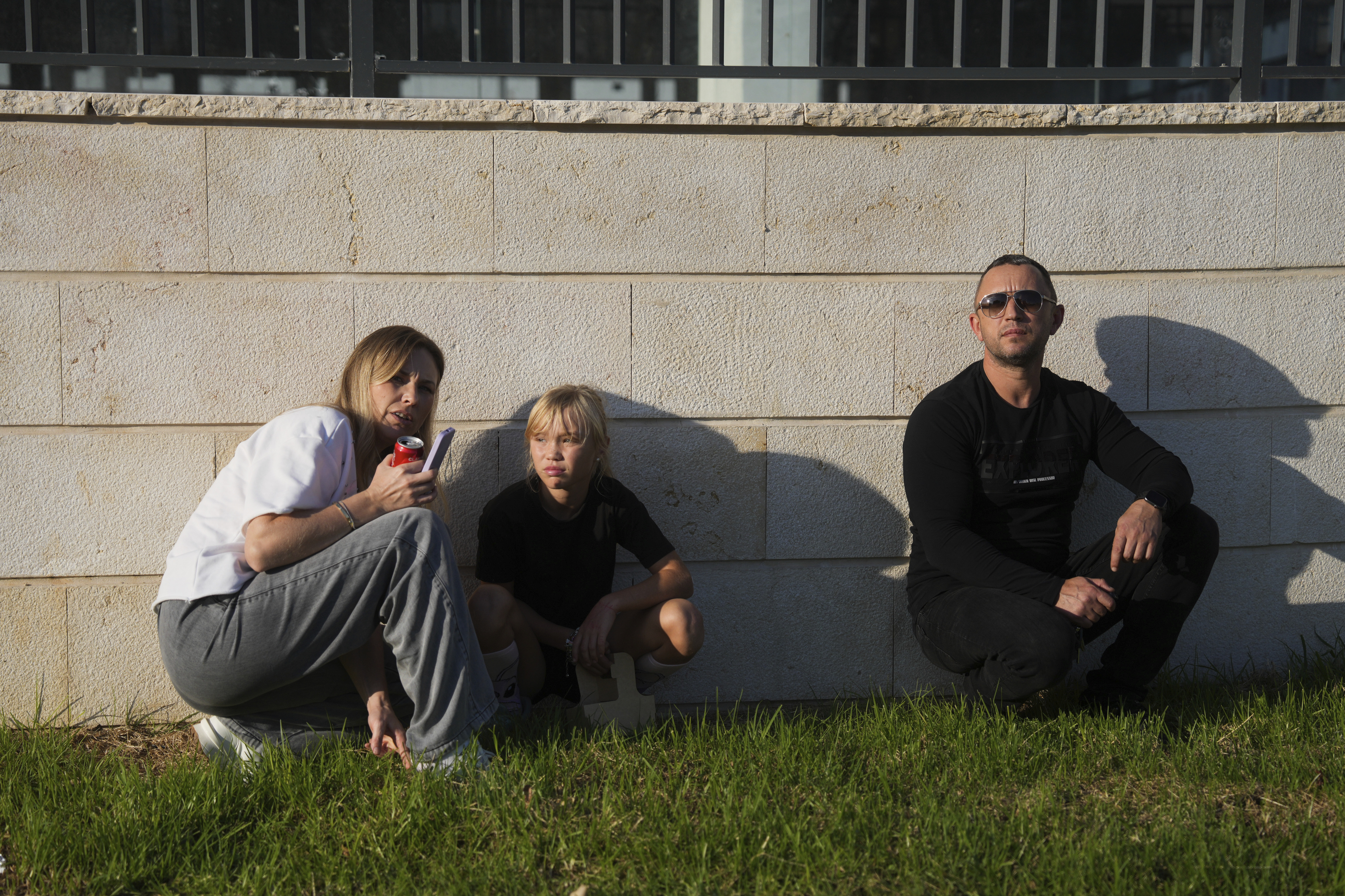 People take cover as a siren sounds a warning of incoming rockets fired from Lebanon, in Kiryat Yam, northern Israel, Wednesday, Nov. 13, 2024. (AP Photo/Ohad Zwigenberg)