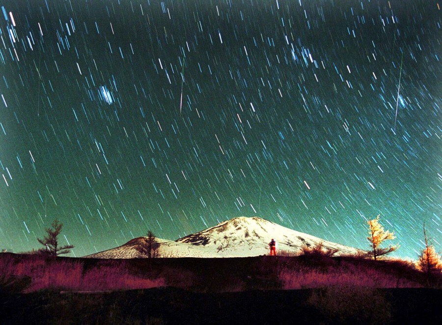 FILE - Leonid meteors are seen streaking across the sky over snow-capped Mount Fuji, Japan's highest mountain, in this 7-minute exposure photo taken, Nov. 19, 2001. (AP Photo/Itsuo Inouye, File)