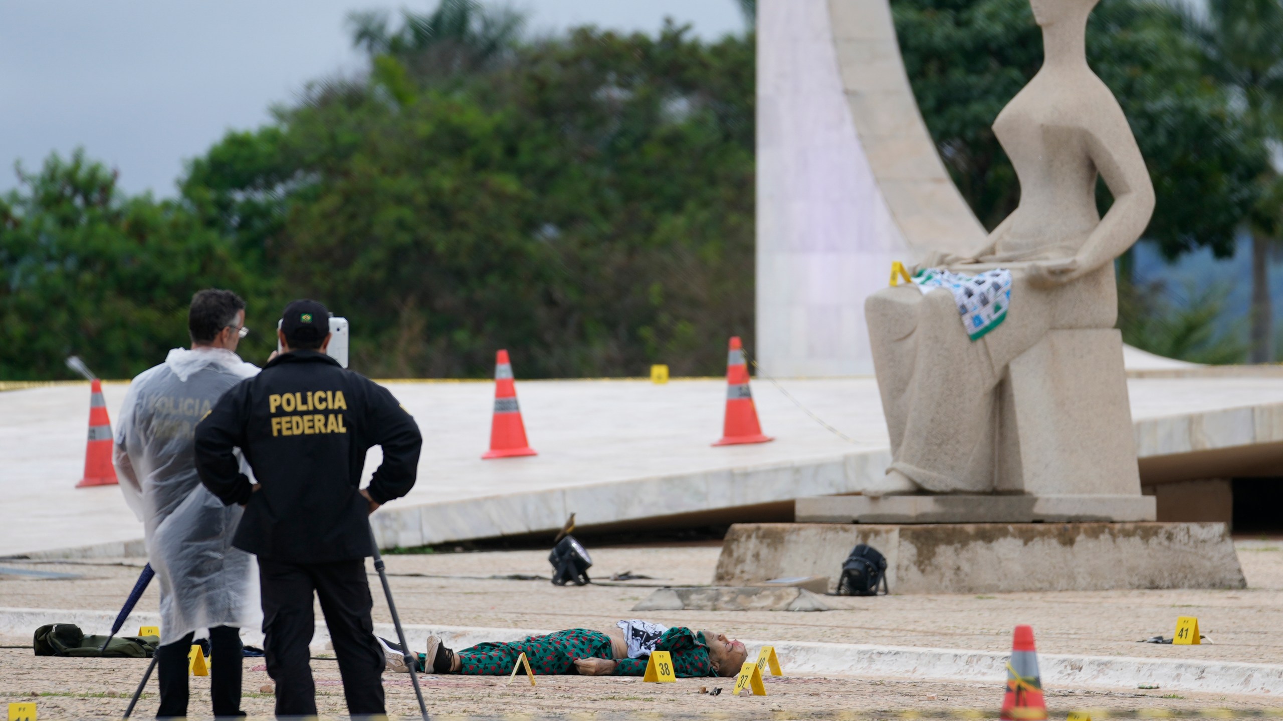 Federal police officers inspect a body outside the Supreme Court following an explosion the previous night, in Brasilia, Brazil, Thursday, Nov. 14, 2024. (AP Photo/Eraldo Peres)