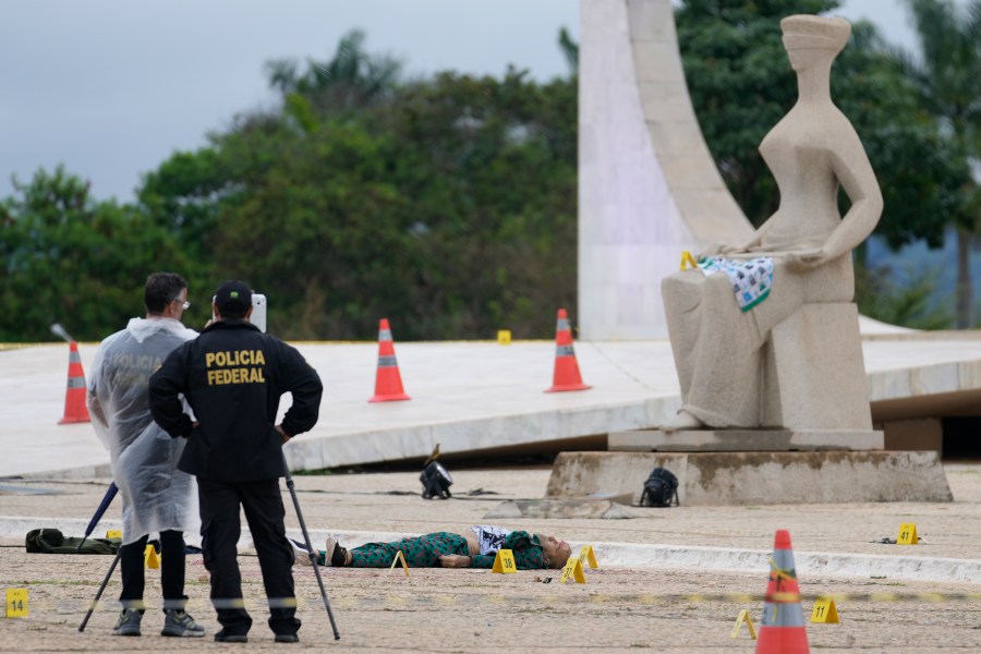 Federal police officers inspect a body outside the Supreme Court following an explosion the previous night, in Brasilia, Brazil, Thursday, Nov. 14, 2024. (AP Photo/Eraldo Peres)