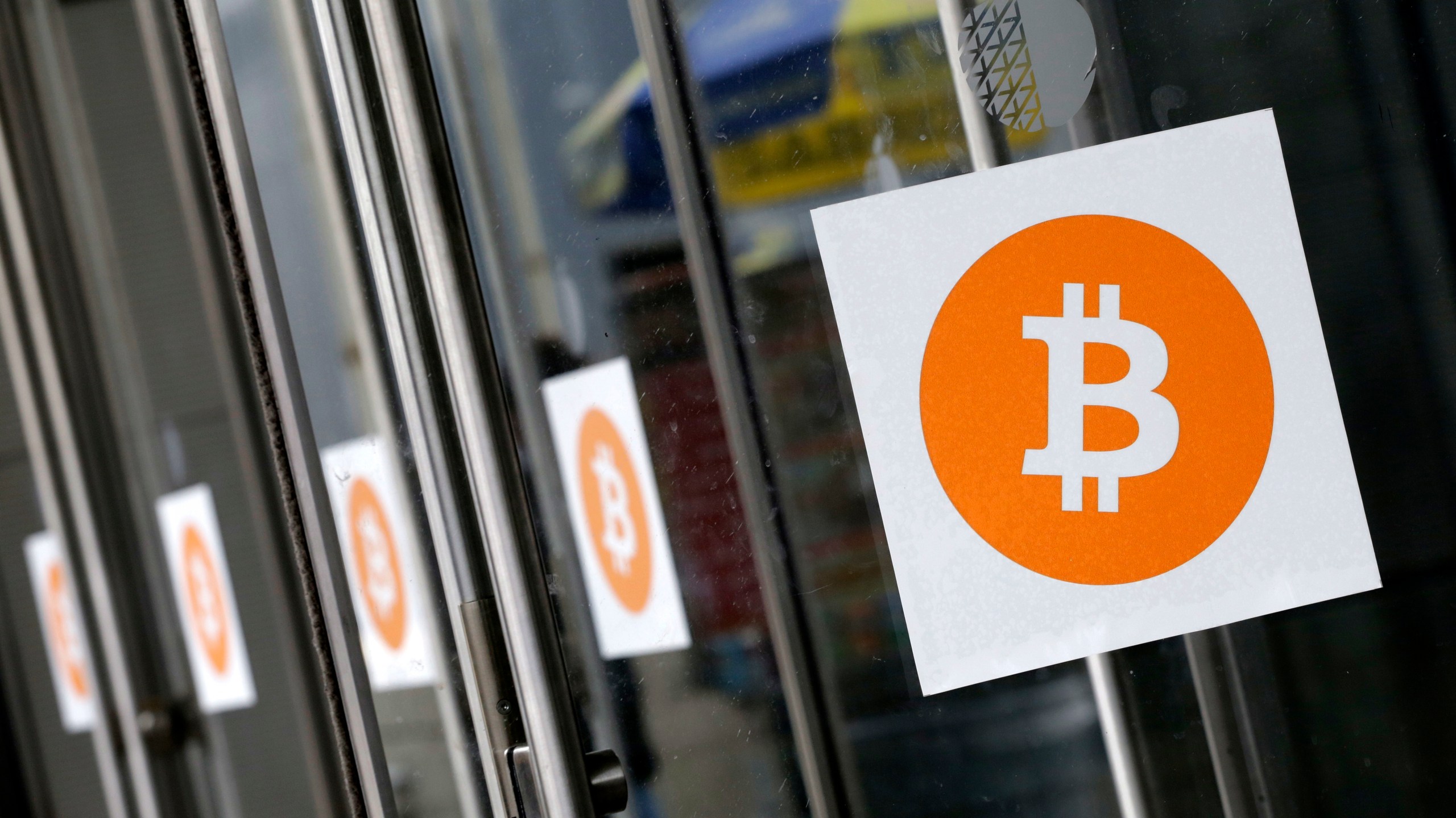 FILE - Bitcoin logos are displayed at the Inside Bitcoins conference and trade show on April 7, 2014, in New York. (AP Photo/Mark Lennihan, File)