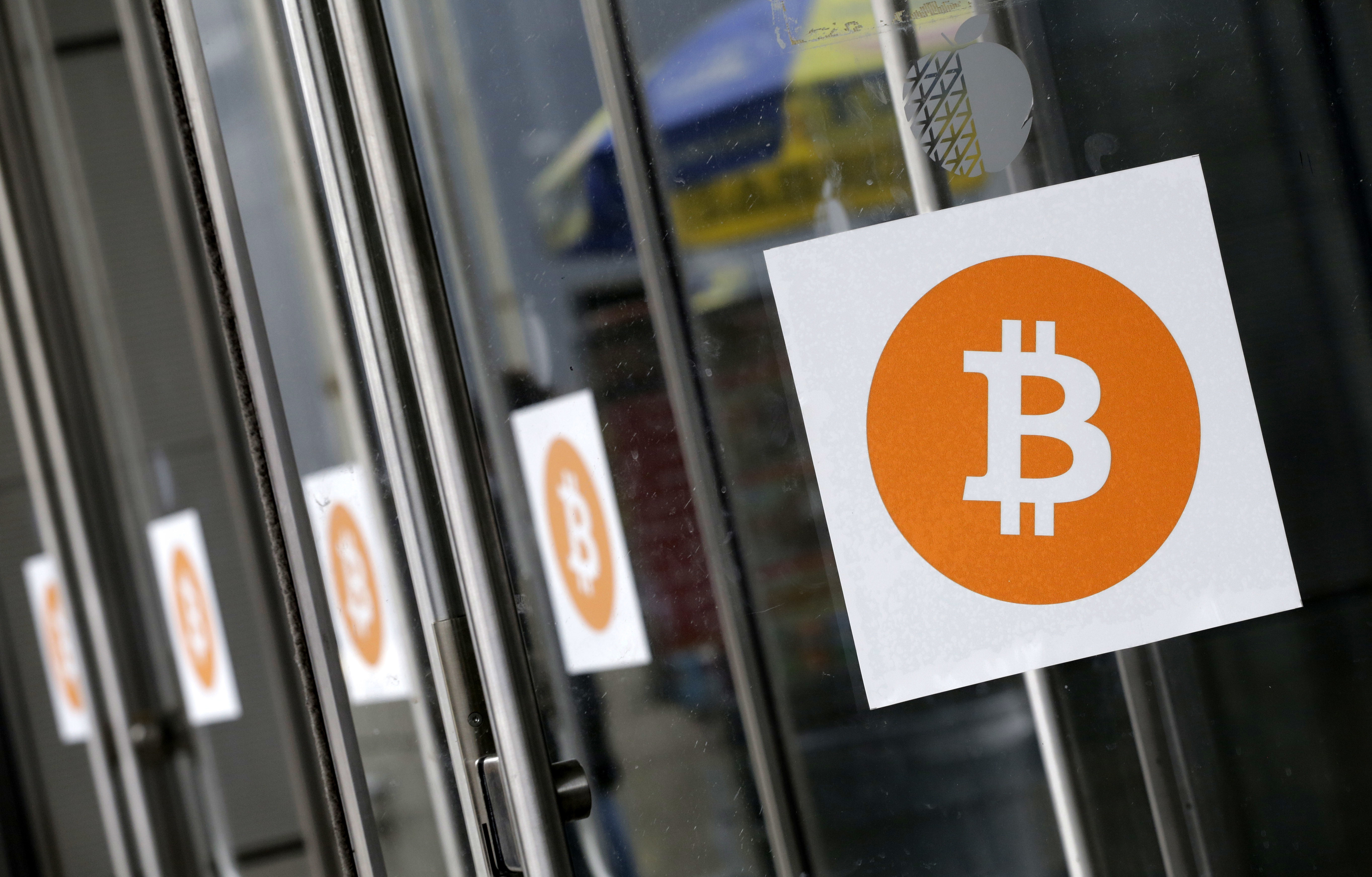 FILE - Bitcoin logos are displayed at the Inside Bitcoins conference and trade show on April 7, 2014, in New York. (AP Photo/Mark Lennihan, File)