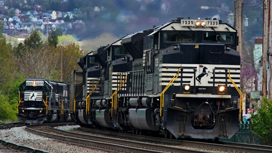 FILE - A Norfolk Southern freight train passes a train on a siding as it approaches a crossing in Homestead, Pa, April 27, 2022. (AP Photo/Gene J. Puskar, File)