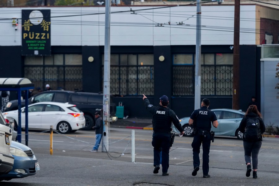 Police officers stand near the scene as they gather security camera footage after multiple people were stabbed in the area Friday, Nov. 8, 2024, in the Chinatown-International District in Seattle. (AP Photo/Lindsey Wasson)