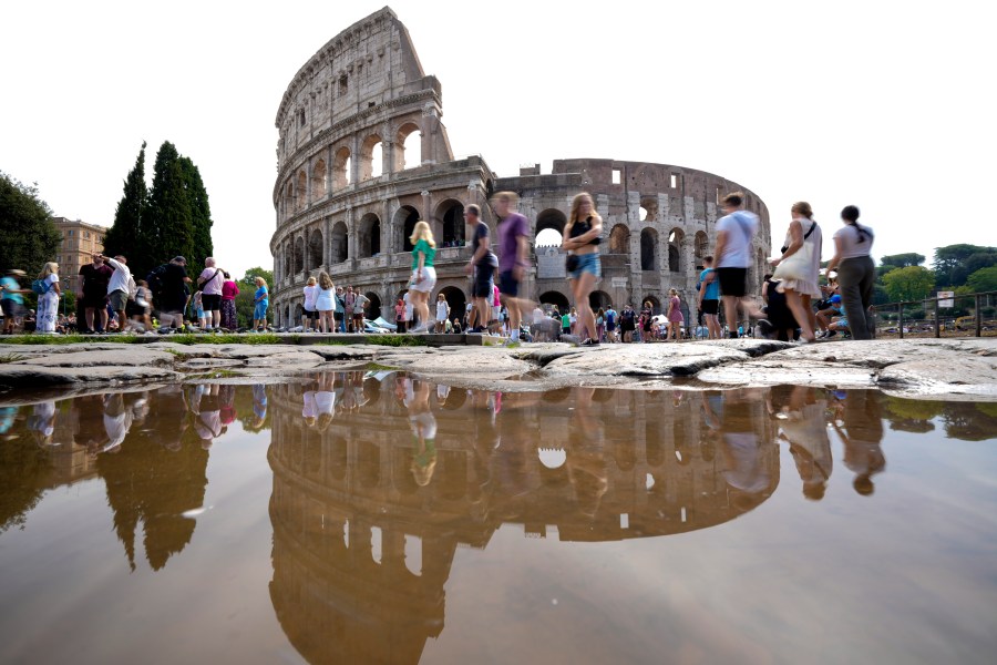 FILE - Tourists walk by the ancient Roman Colosseum as it's reflected in a puddle, in Rome, Sept. 5, 2024. (AP Photo/Andrew Medichini, file)