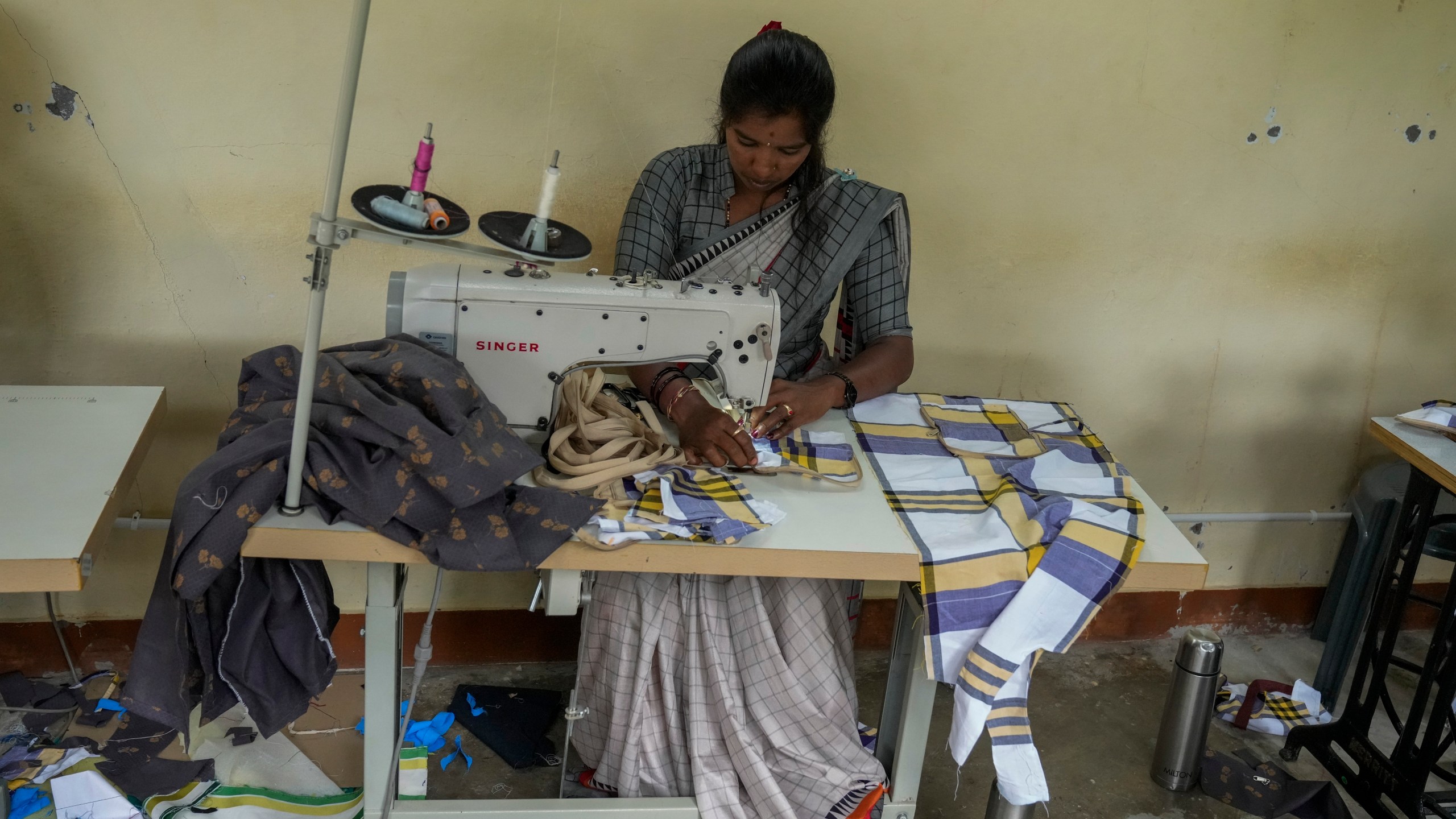 H. Gauri, 32, uses an electric sewing machine to stitch a cloth pouch in a small garage at the campus of the Swami Vivekananda Youth Movement, a nongovernmental organization that works to help poor and Indigenous communities, in Kenchanahalli, India, Monday, Sept. 23, 2024. (AP Photo/Aijaz Rahi)