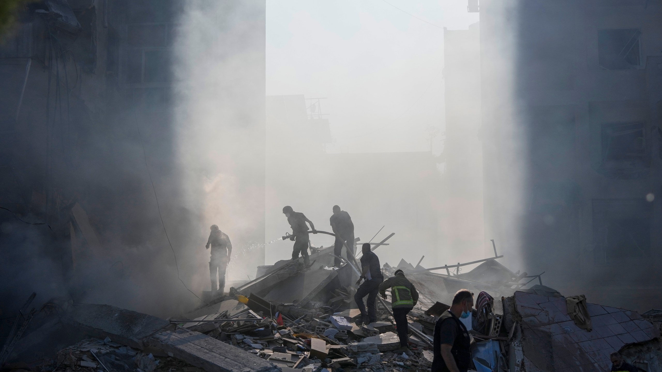 Civil defense workers extinguish a fire as smoke rises from the site of an Israeli airstrike in Tayouneh, Beirut, Lebanon, Friday, Nov. 15, 2024. (AP Photo/Hassan Ammar)