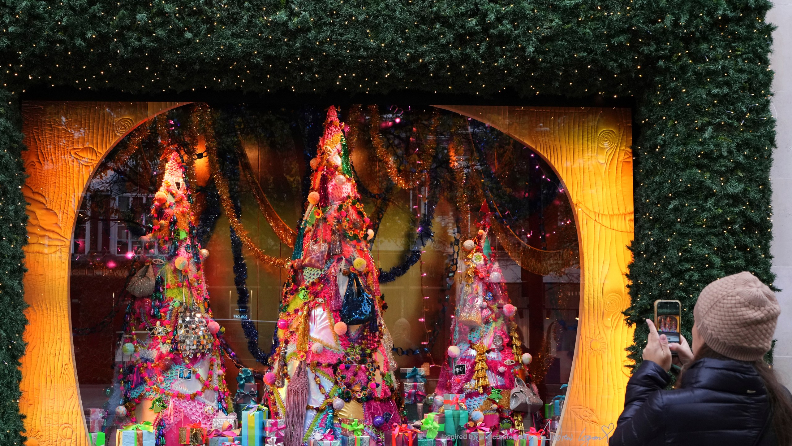 A woman photographs a festive shop window in Oxford Street in London, Friday, Nov. 15, 2024. (AP Photo/Kirsty Wigglesworth)