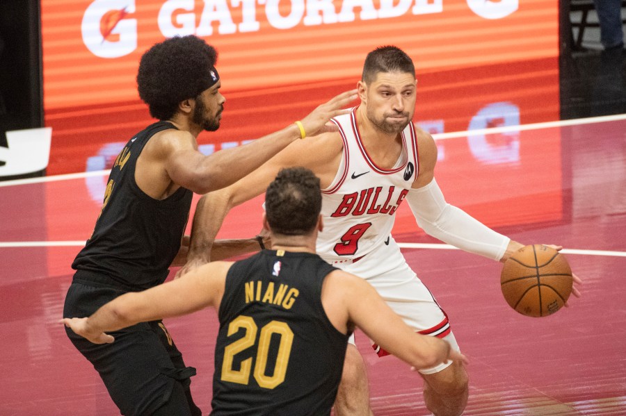 Chicago Bulls' Nikola Vucevic (9) is defended by Cleveland Cavaliers' Jarrett Allen, left, and Georges Niang (20) during the first half of an Emirates NBA cup basketball game in Cleveland, Friday, Nov 15, 2024. (AP Photo/Phil Long)