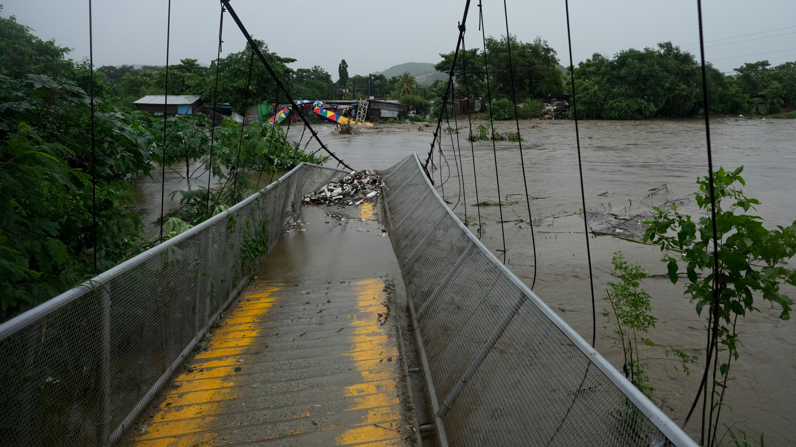 A pedestrian bridge collapsed due to flooding caused by rains brought on by Tropical Storm Sara in San Pedro Sula, Honduras Saturday, Nov. 16, 2024. (AP Photo/Moises Castillo)