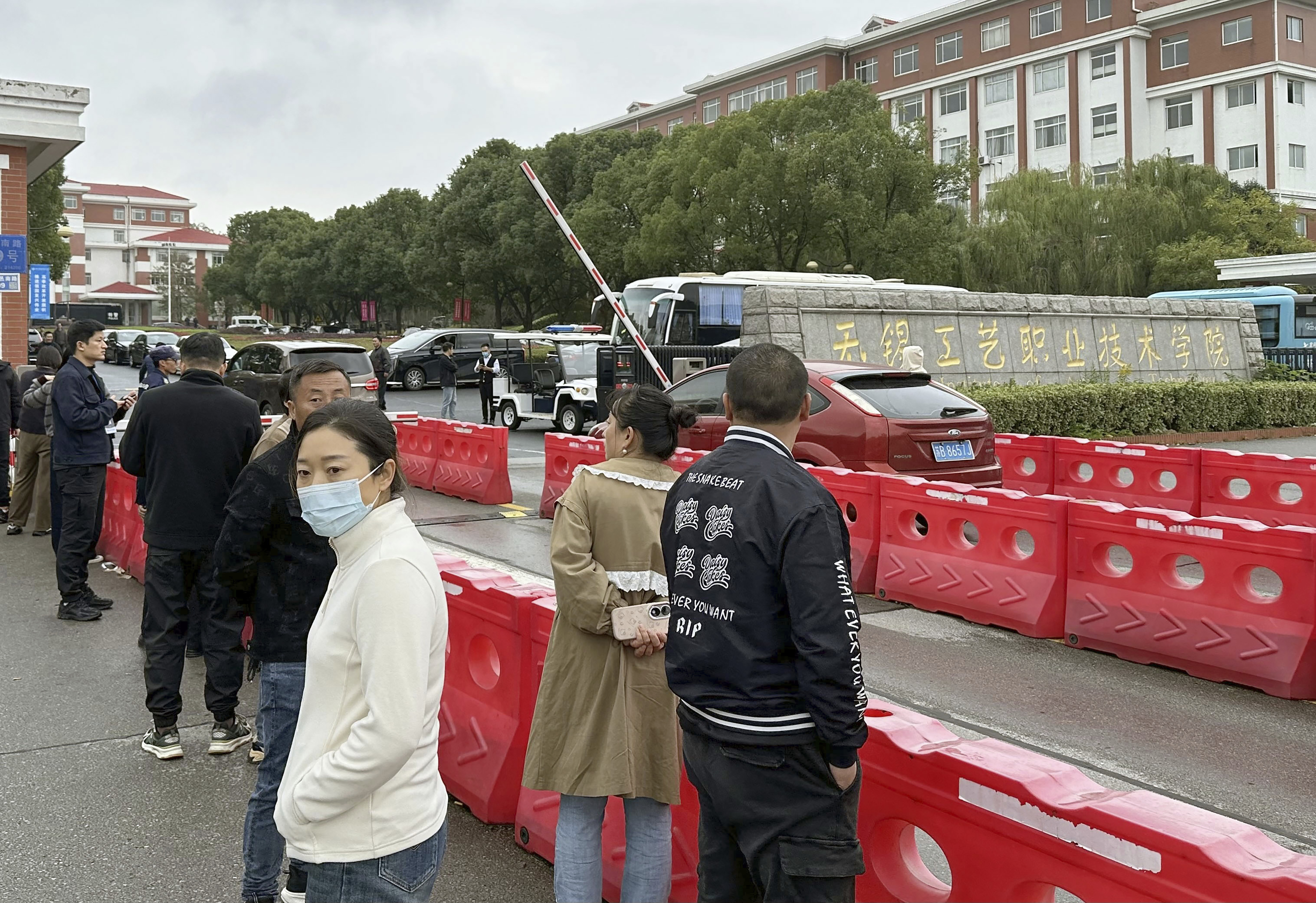 Guardians gather in front of the Wuxi Vocational Institute of Arts and Technology in Yixing, eastern Chinese city of Wuxi Sunday, Nov. 17, 2024, a day after a stabbing attack took place. (Kyodo News via AP)