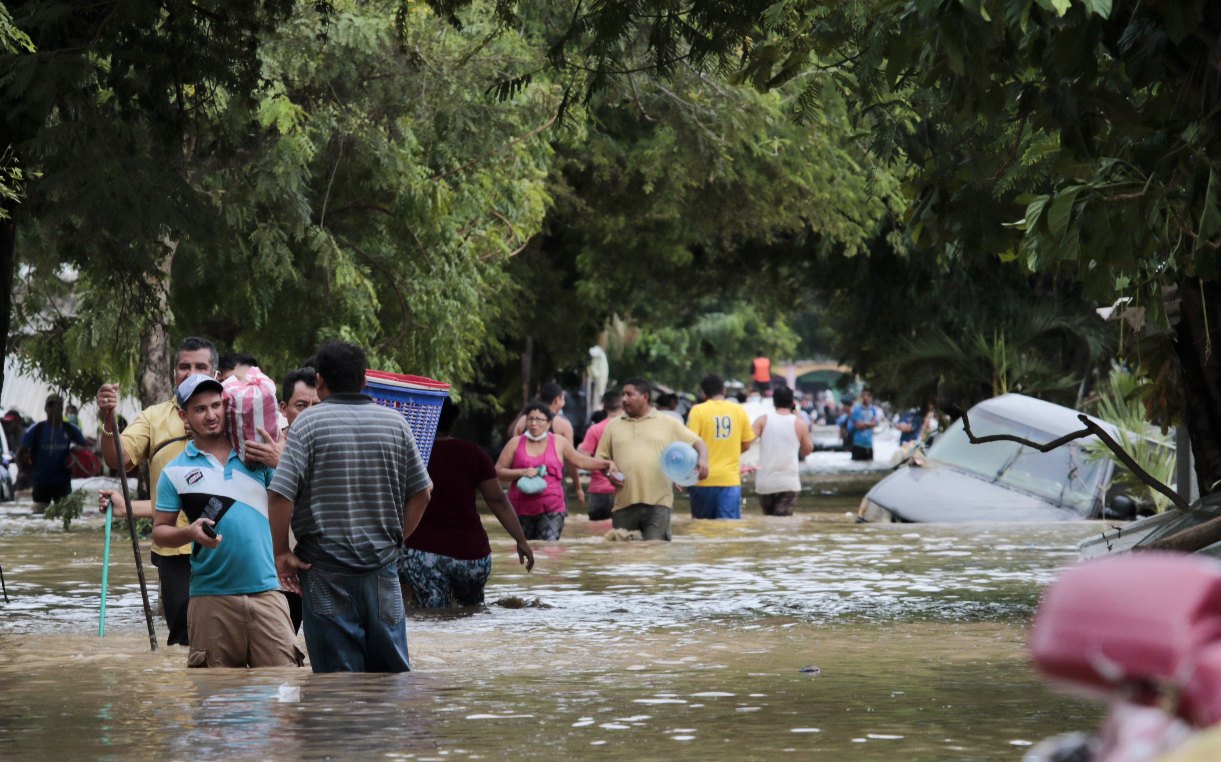 FILE - Residents walk past inundated vehicles in the flooded streets of Planeta, Honduras, Nov. 6, 2020, in the aftermath of Hurricane Eta. (AP Photo/Delmer Martinez, File)