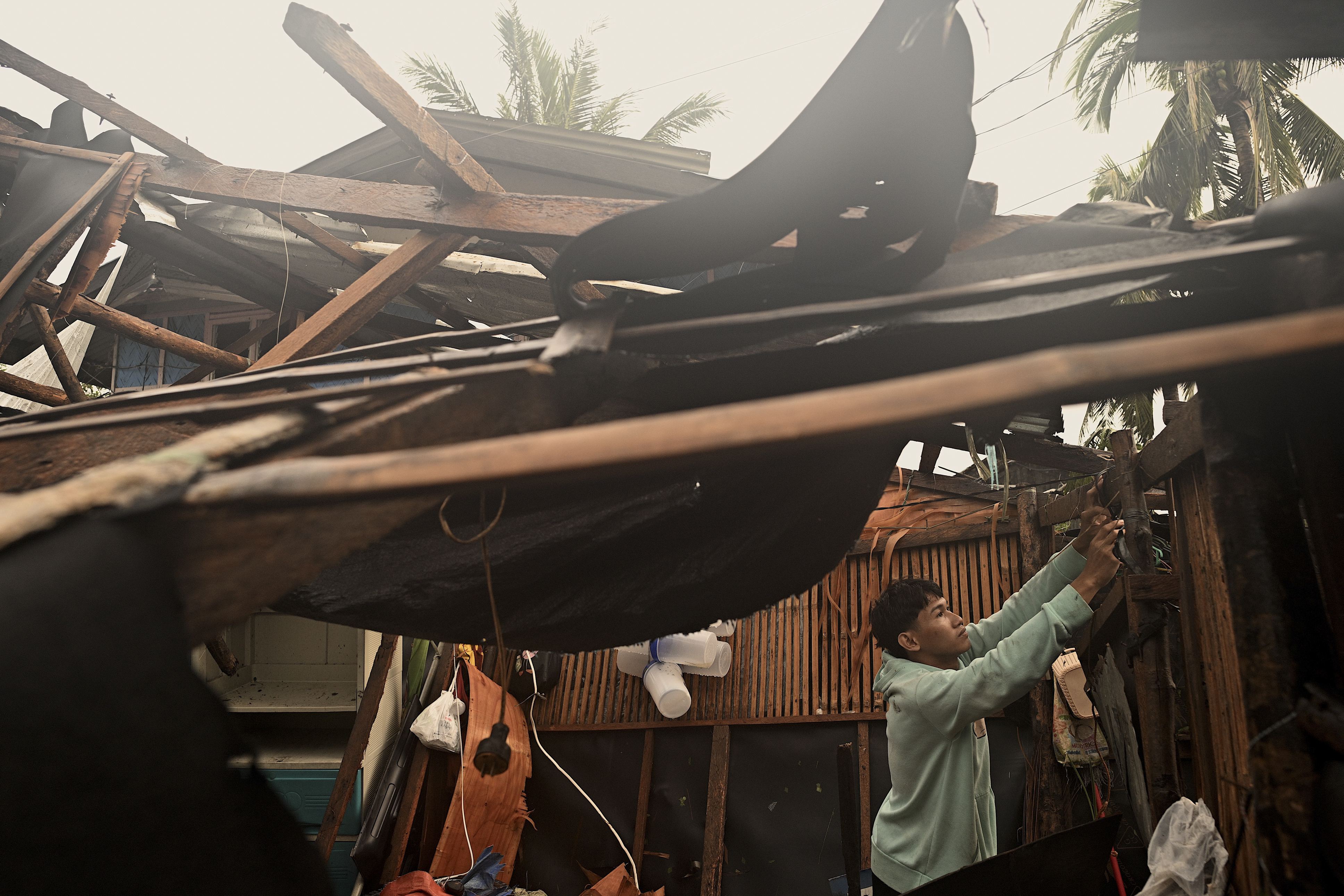 A resident checks belongings from his damaged home that was blown off by strong winds caused by Typhoon Man-yi in the municipality of Baler, Aurora province, northeastern Philippines Monday, Nov. 18, 2024. (AP Photo/Noel Celis)