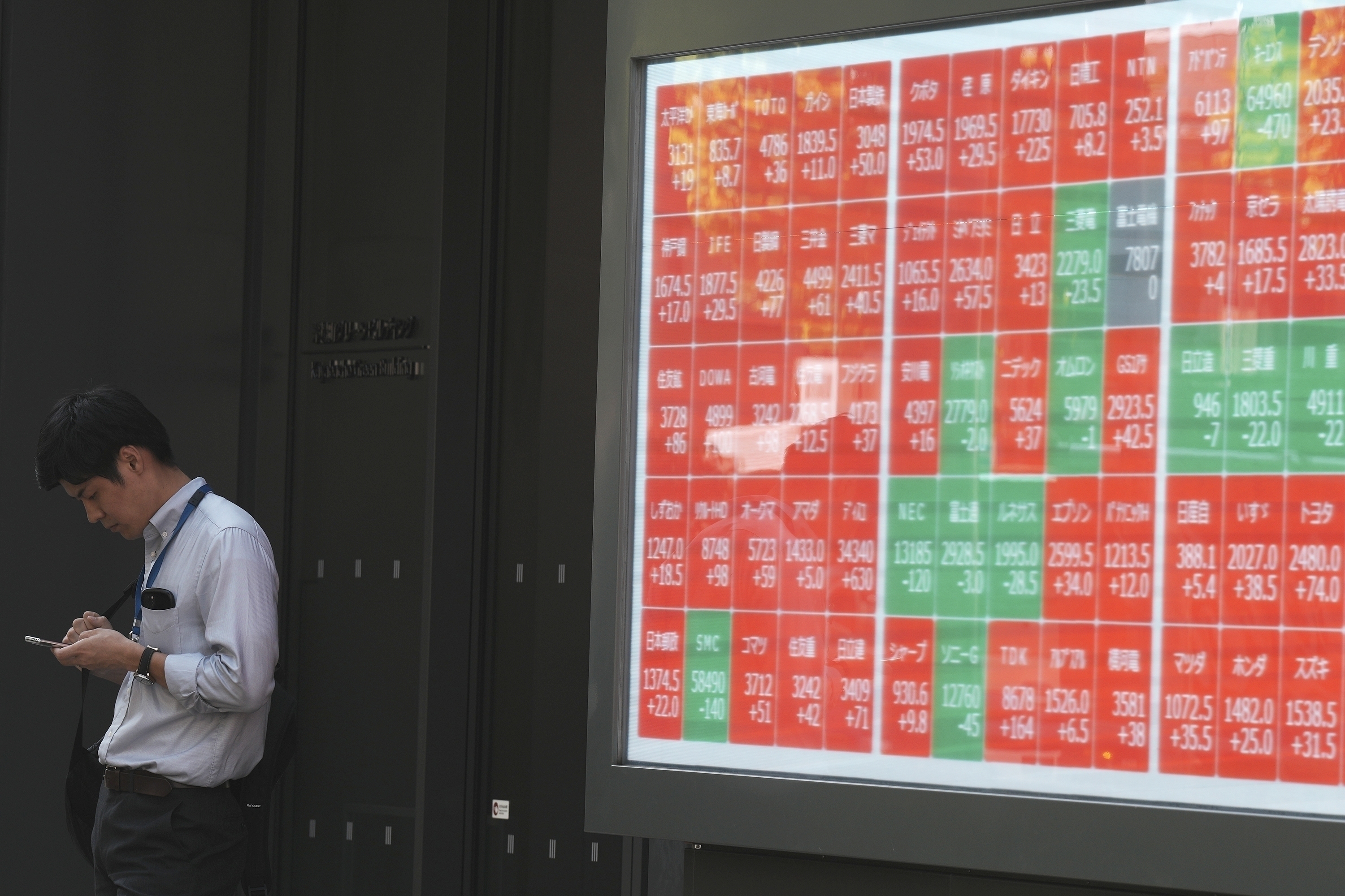 FILE - A person stands near an electronic stock board showing Japan's Nikkei index at a securities firm in Tokyo, on Sept. 18, 2024. (AP Photo/Eugene Hoshiko, File)