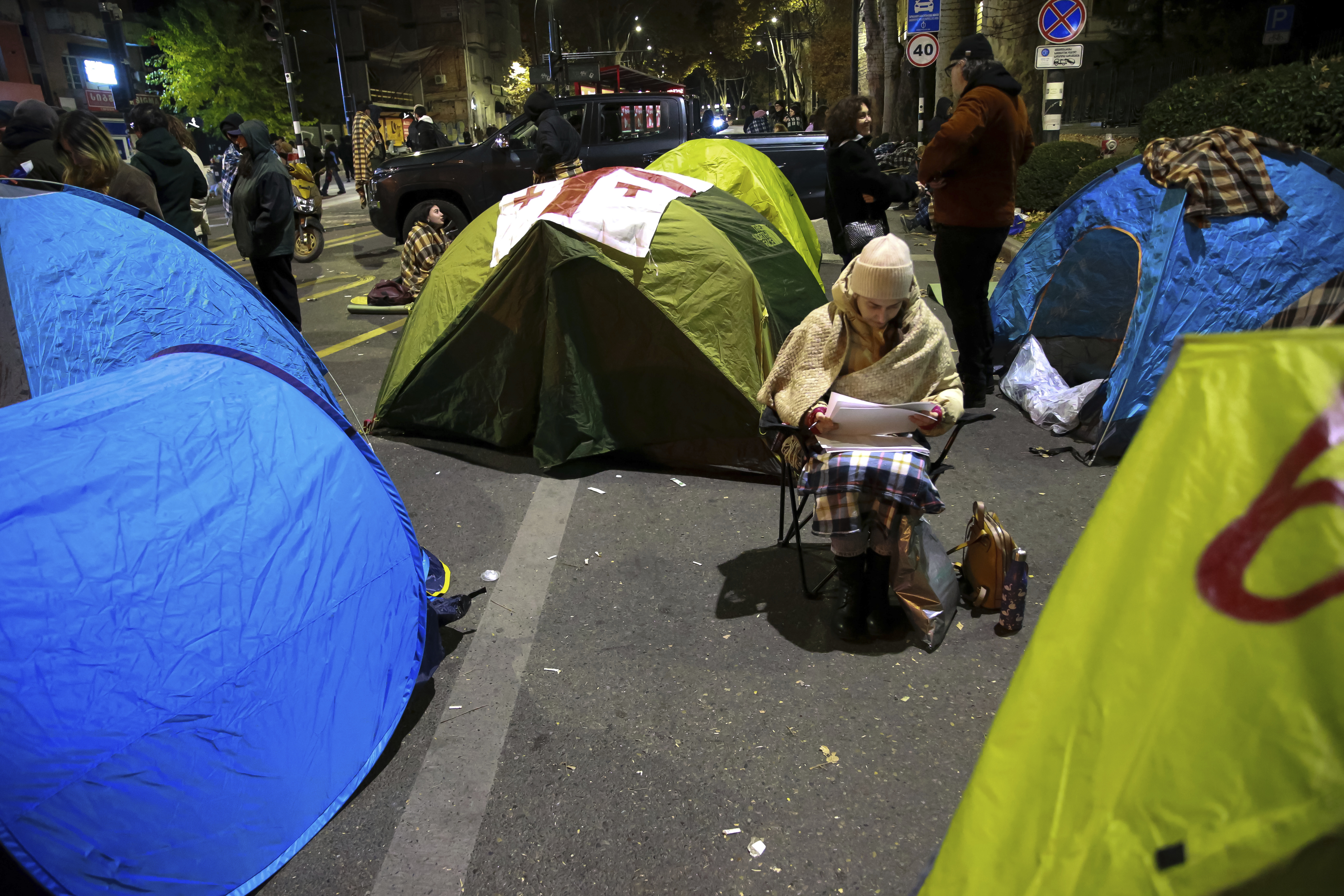 A protester sits between tents during a rally against the results of the parliamentary elections amid allegations that the vote was rigged in Tbilisi, Georgia, early Monday, Nov. 18, 2024. (AP Photo/Zurab Tsertsvadze)