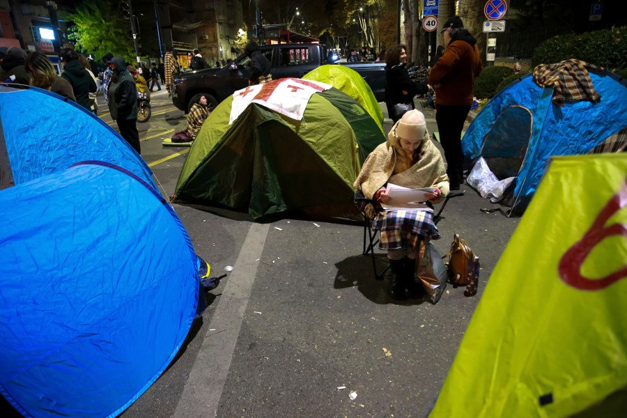 A protester sits between tents during a rally against the results of the parliamentary elections amid allegations that the vote was rigged in Tbilisi, Georgia, early Monday, Nov. 18, 2024. (AP Photo/Zurab Tsertsvadze)