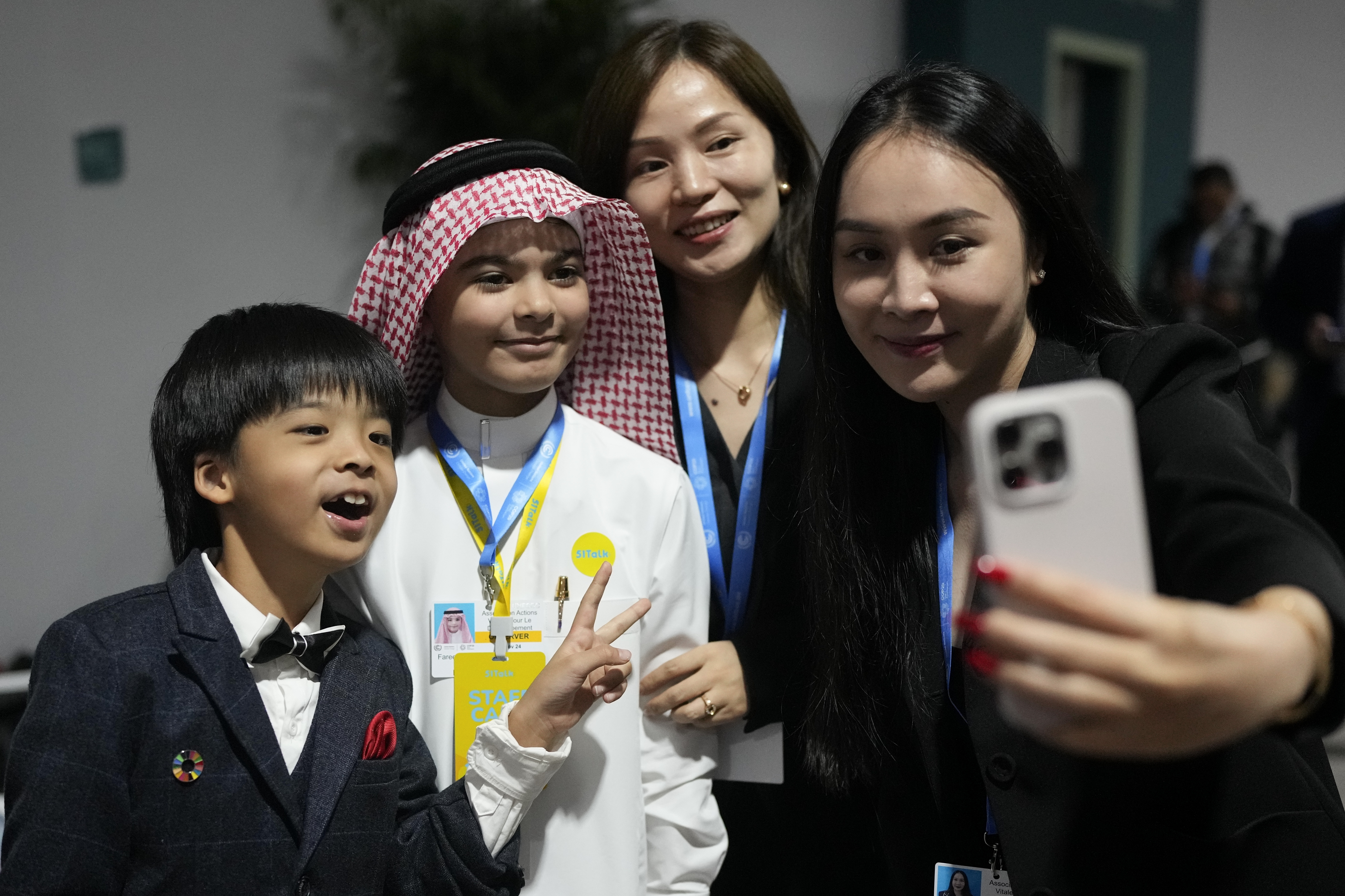 Huang Jiangcheng, from China, left, and Fareed Mohammed Felemban, from Saudi Arabia, pose for photos after speaking at a youth session during the COP29 U.N. Climate Summit, Monday, Nov. 18, 2024, in Baku, Azerbaijan. (AP Photo/Rafiq Maqbool)