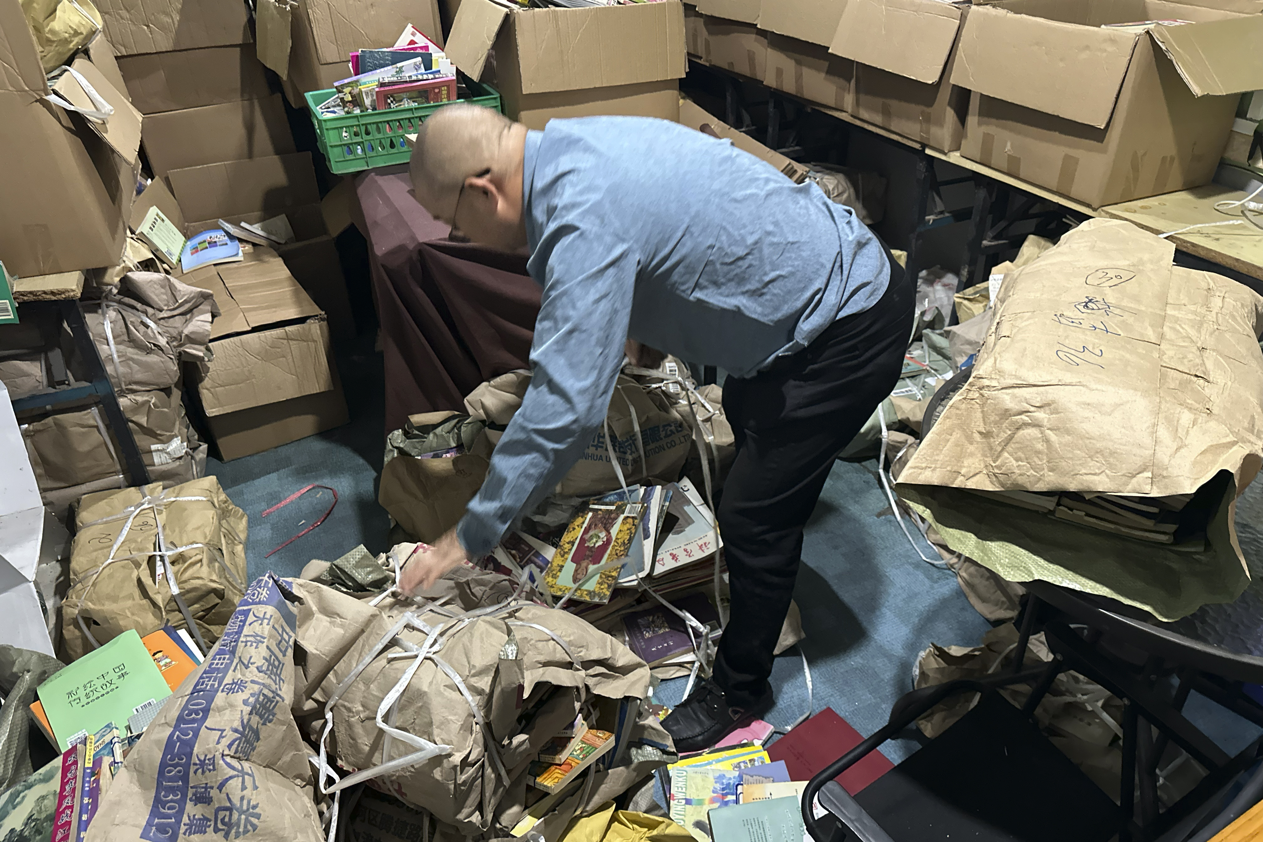 Secondhand bookstore owner Wang Yingxing bundles books at a storage shed near his shuttered shop in Ningbo, in eastern China's Zhejiang province, Oct. 9, 2024. (AP Photo/Dake Kang)