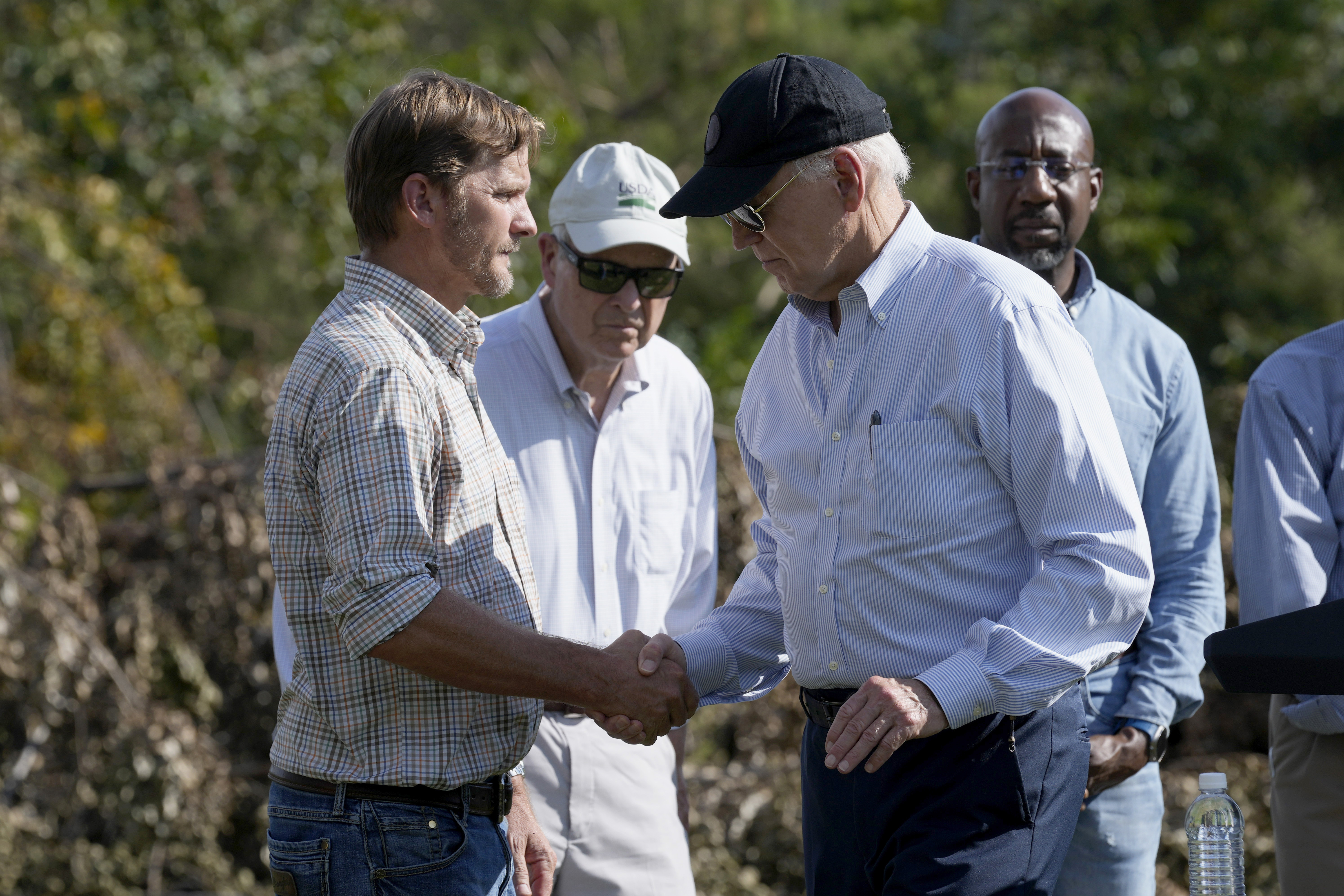 FILE - President Joe Biden, right, shakes hands with Buck Paulk, property manager of Shiloh Pecan Farm, after he spoke at the farm in Ray City, Ga., Oct. 3, 2024, as part of his trip to see areas impacted by Hurricane Helene. Looking on at right is Sen. Raphael Warnock, D-Ga. (AP Photo/Susan Walsh, File)