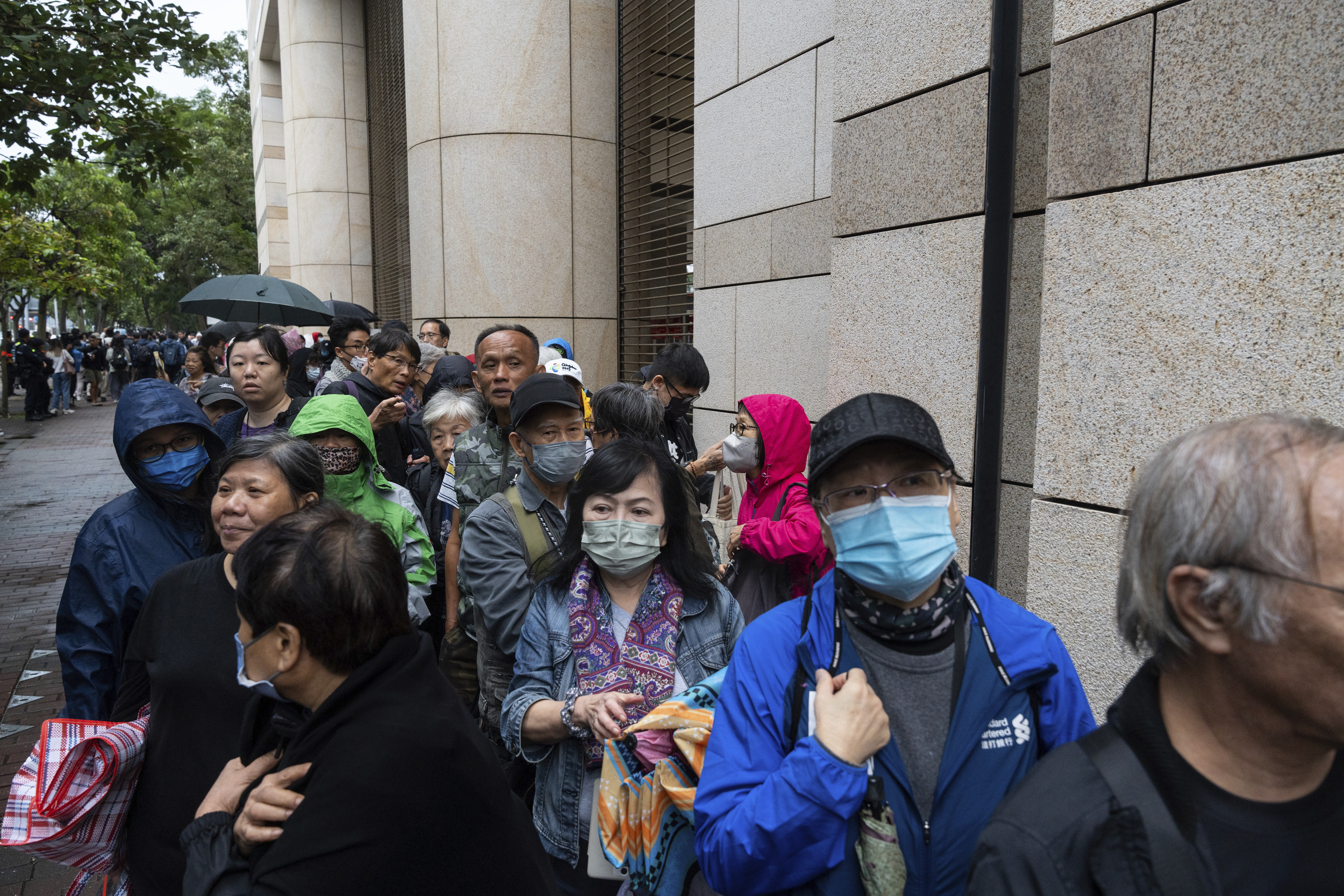 People wait outside the West Kowloon Magistrates' Courts in Hong Kong Tuesday, Nov. 19, 2024, ahead of the sentencing in national security case. (AP Photo/Chan Long Hei)