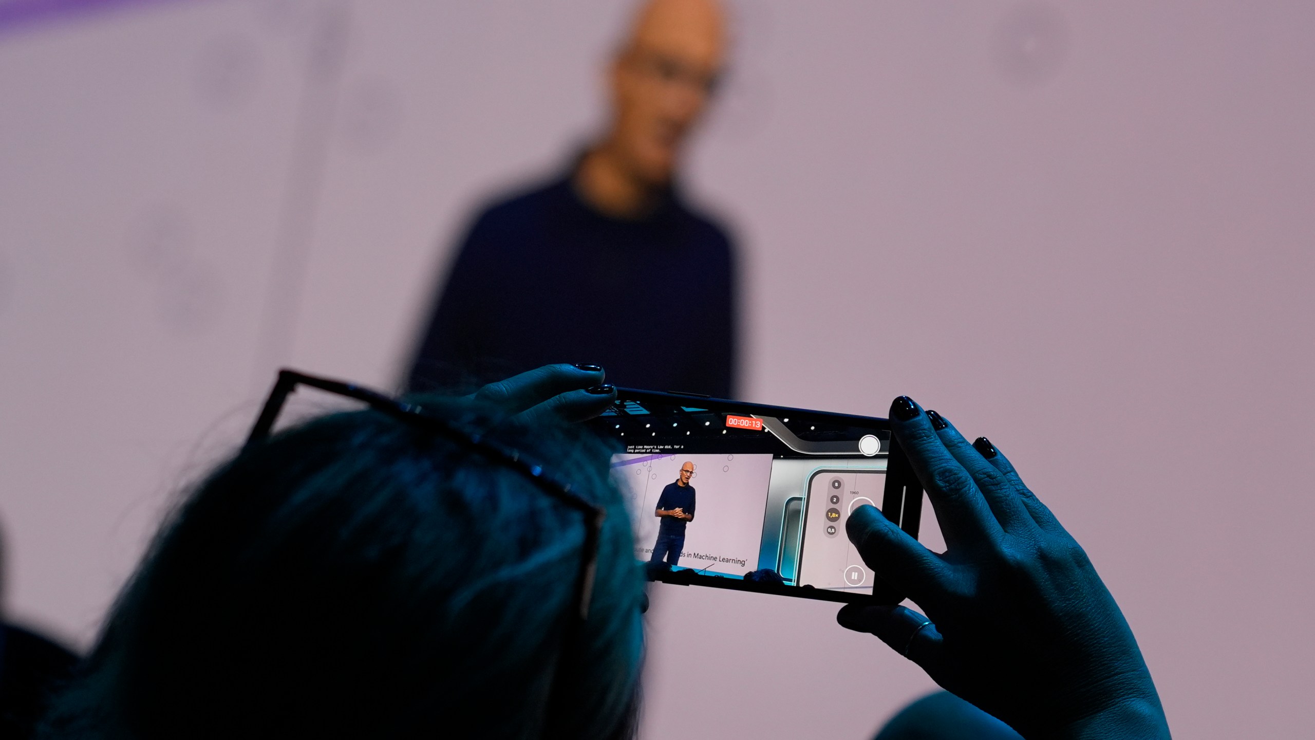 An attendee at the Microsoft Ignite conference records CEO Satya Nadella as he delivers the keynote address at the conference Tuesday, Nov. 19, 2024, in Chicago. (AP Photo/Charles Rex Arbogast)