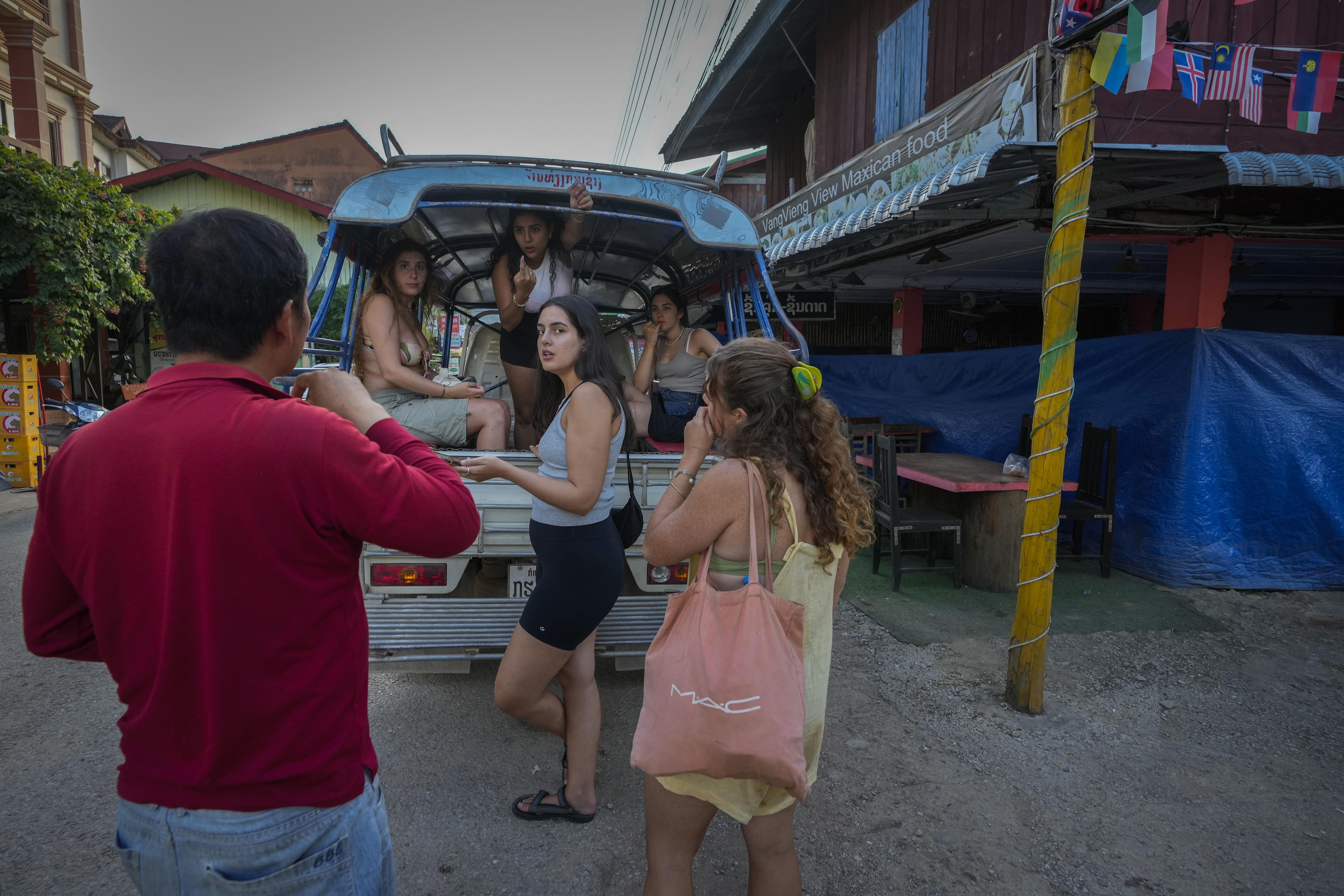 Tourists talk to a bar owner in Vang Vieng, Laos, Tuesday, Nov. 19, 2024. (AP Photo/Anupam Nath)