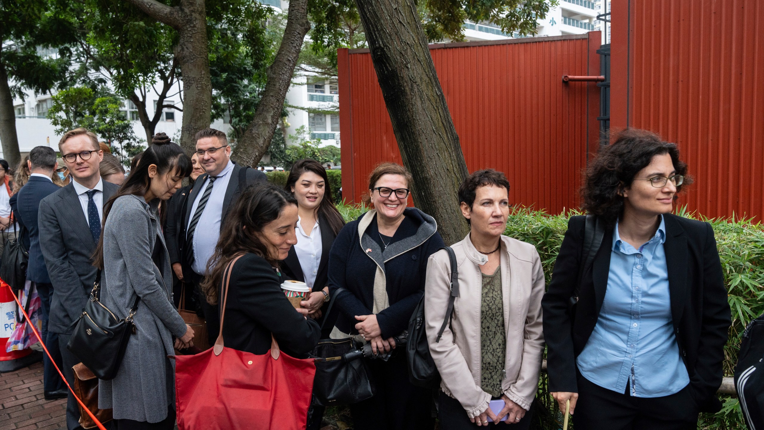 Representatives from various consulates wait in line outside the West Kowloon Magistrates' Courts in Hong Kong Tuesday, Nov. 19, 2024, ahead of the sentencing in national security case. (AP Photo/Chan Long Hei)