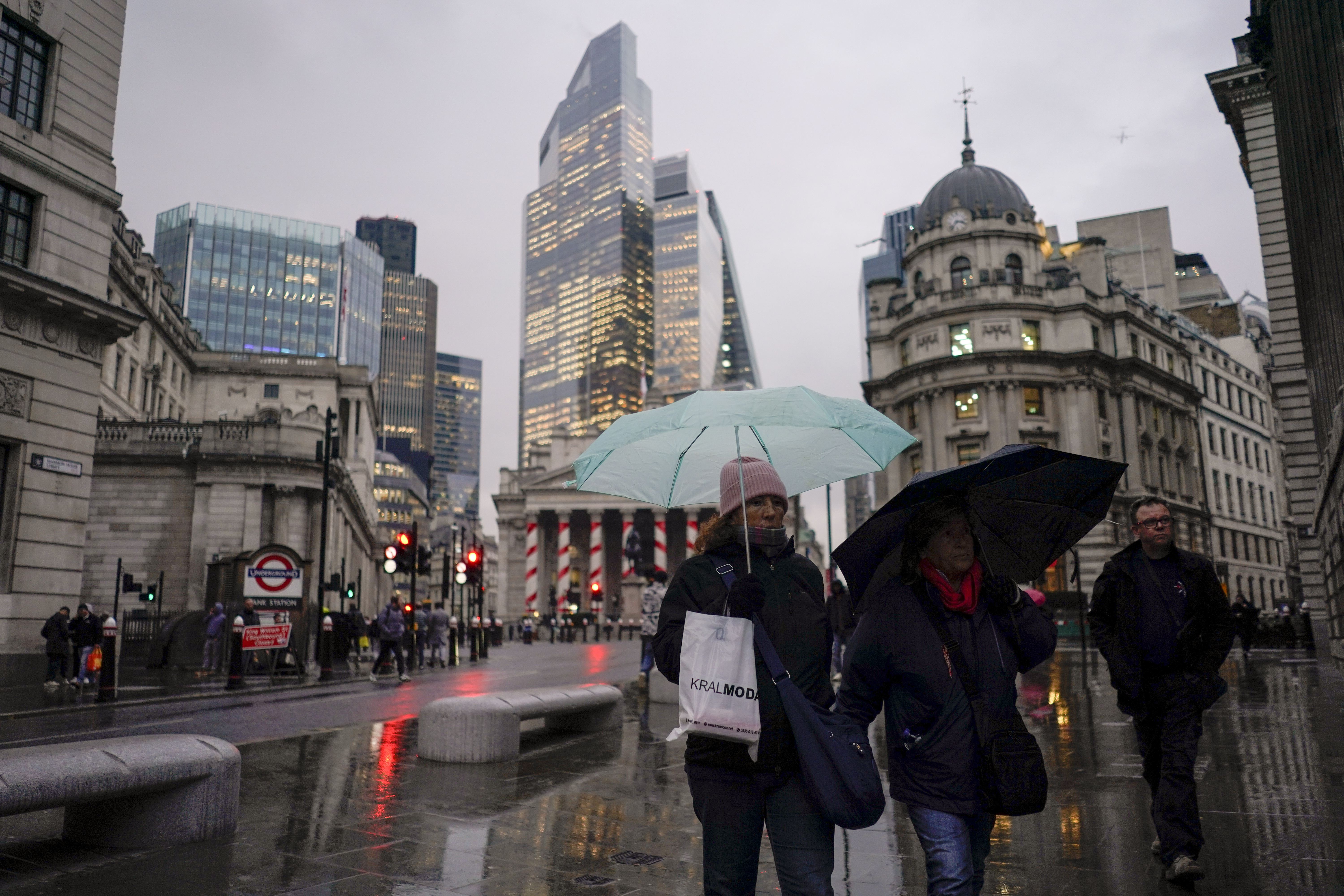 People hold umbrellas as they walk in front of the Bank of England, at the start of a week that is set to see the temperatures drop, in London, Monday, Nov. 18, 2024. (AP Photo/Alberto Pezzali)