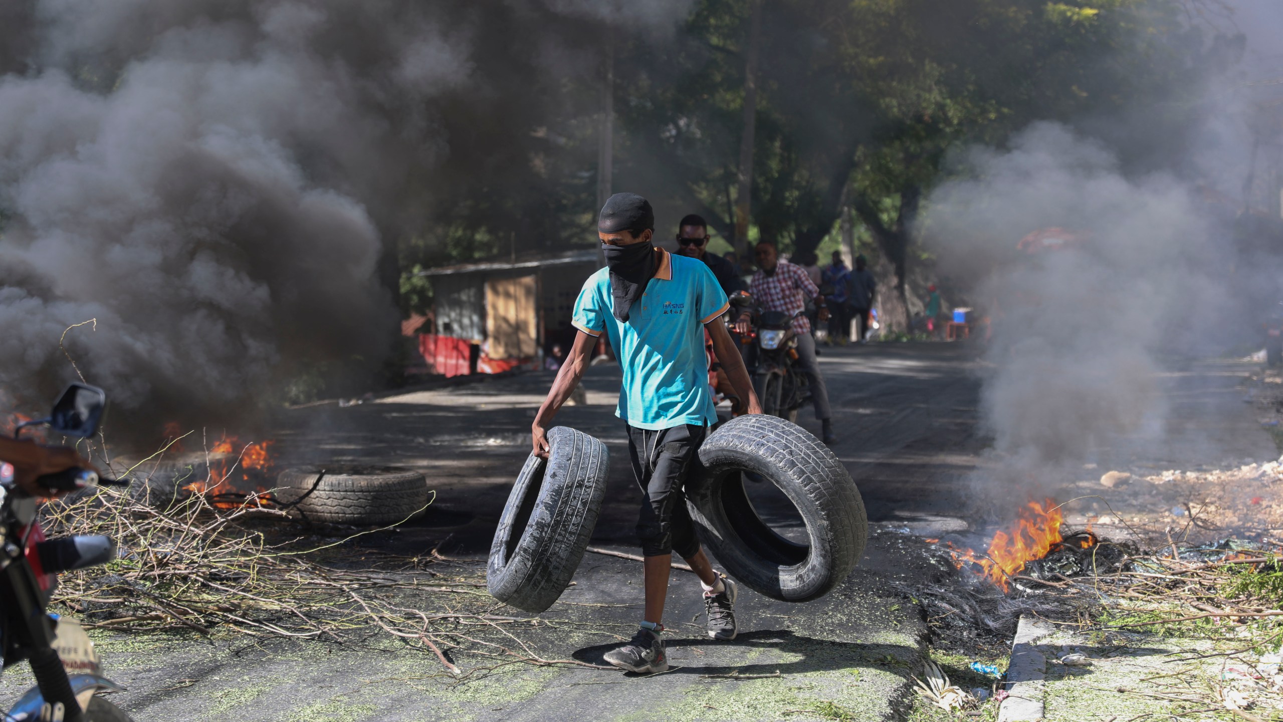 A resident carries tires to be added to a burning barricade to deter gang members from entering his neighborhood, in Port-au-Prince, Haiti, Tuesday, Nov. 19, 2024. (AP Photo/Odelyn Joseph)