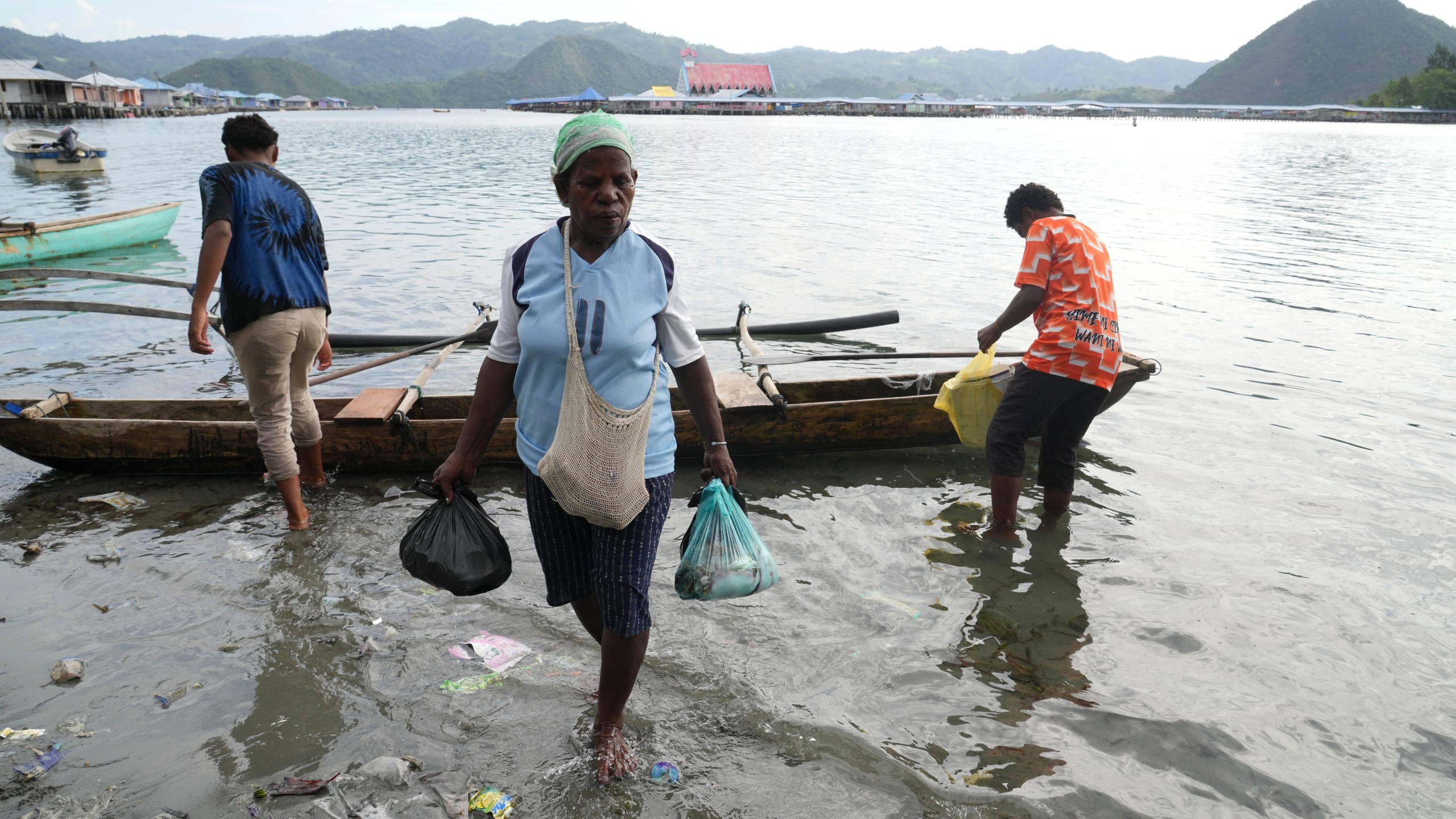 A woman carries fish in plastic bags to a market at Enggros village in Jayapura, Papua province, Indonesia on Wednesday, Oct. 2, 2024. (AP Photo/Firdia Lisnawati)