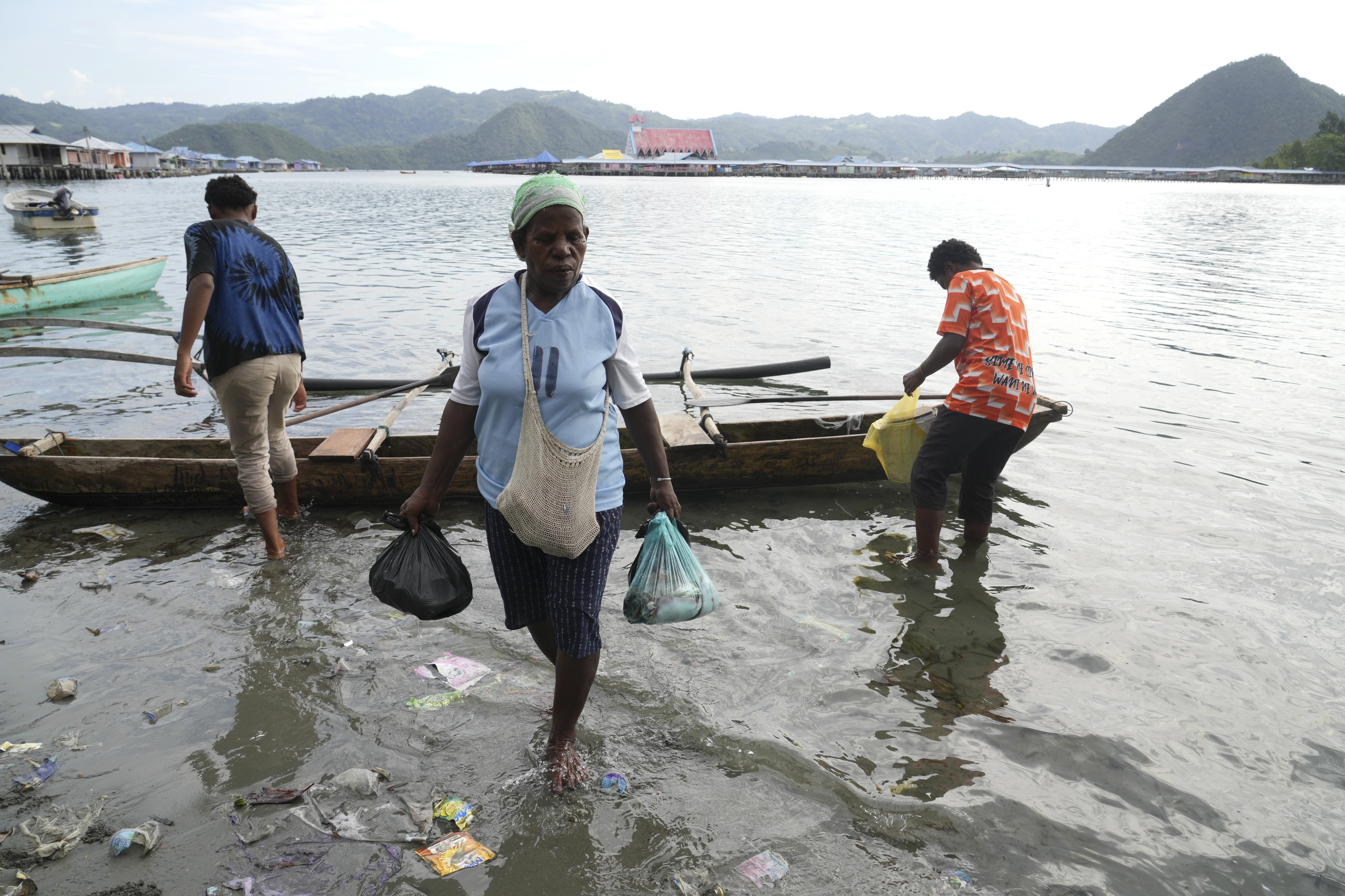 A woman carries fish in plastic bags to a market at Enggros village in Jayapura, Papua province, Indonesia on Wednesday, Oct. 2, 2024. (AP Photo/Firdia Lisnawati)