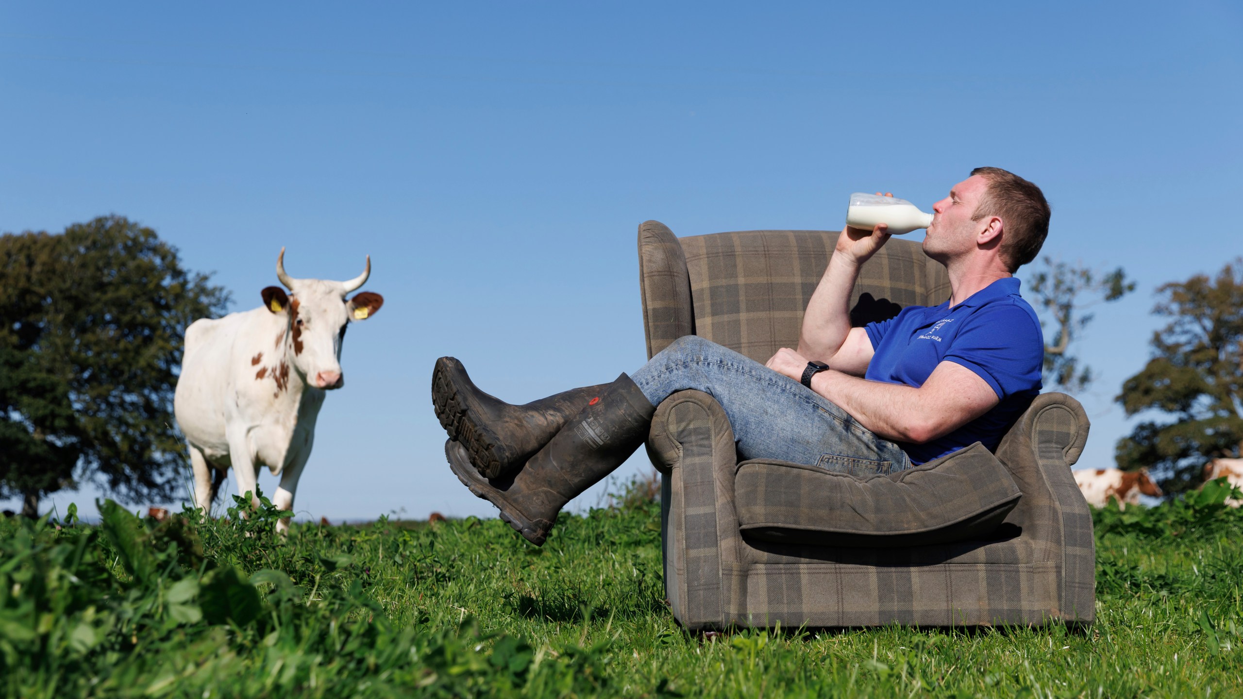 This undated handout photo shows Bryce Cunningham, farmer and owner of Mossgiel Organic Farm near Mauchline, as he poses drinking milk in a field with some of his herd of Ayrshire cows at Mossgiel Organic Farm, Mauchline, Scotland. (Mossgiel Organic Dairy via AP)